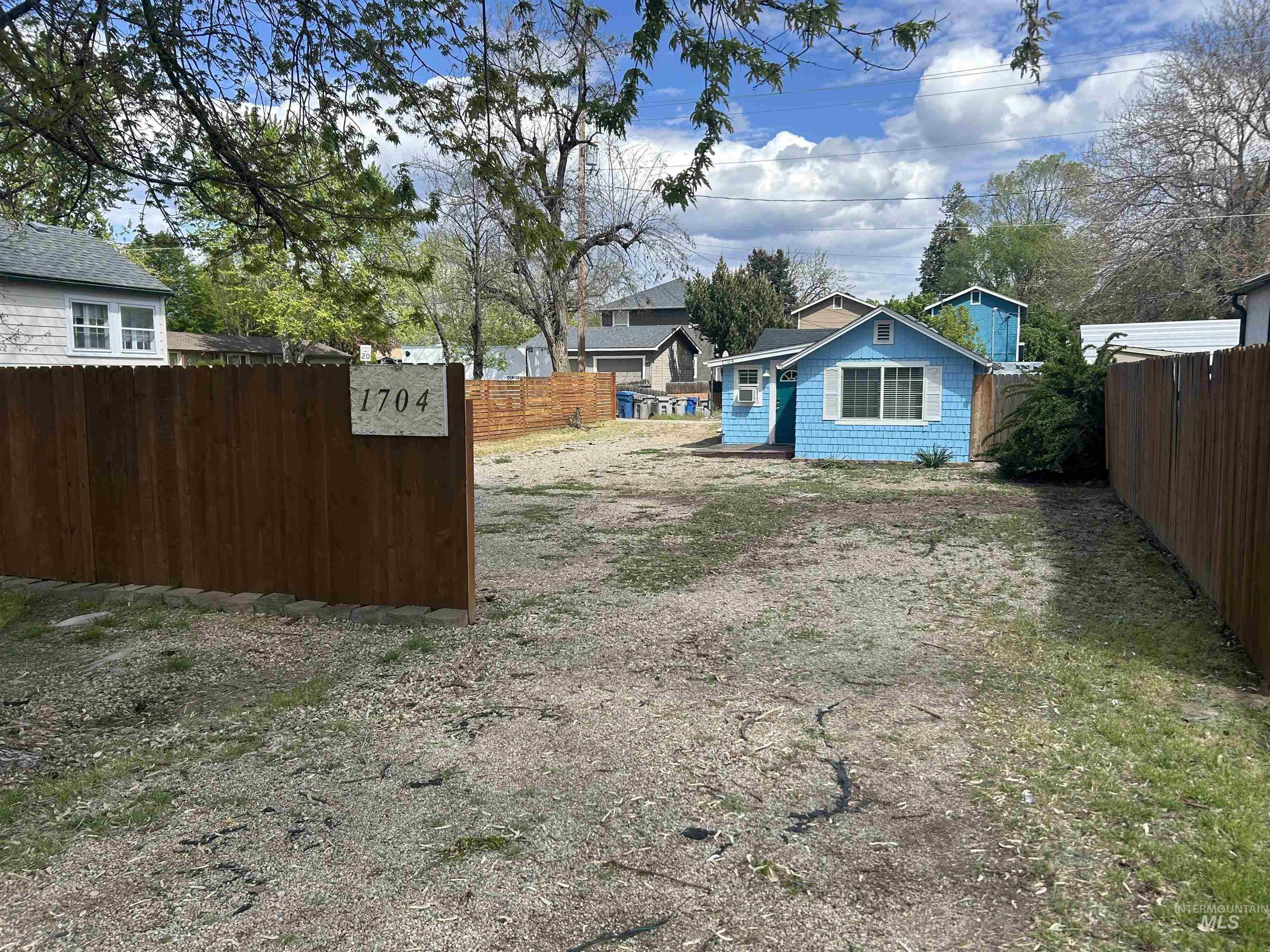 Spacious lot featuring a wood fence, a blue-sided structure, and a secondary structure