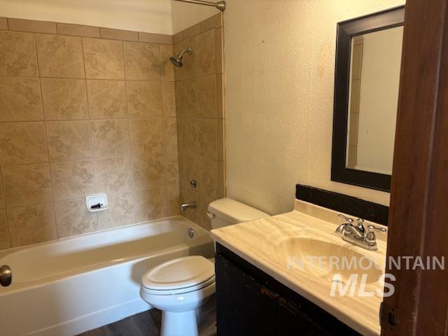 Bathroom featuring vanity, shower / tub combination, and a textured wall