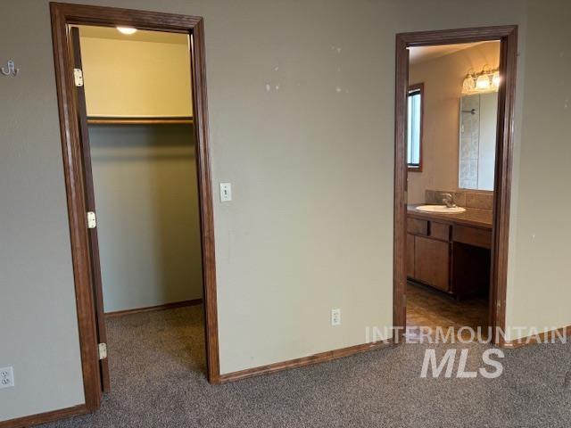 Unfurnished bedroom featuring a walk in closet and dark carpet