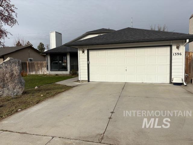 View of front of property featuring driveway, a garage, a chimney, and roof with shingles