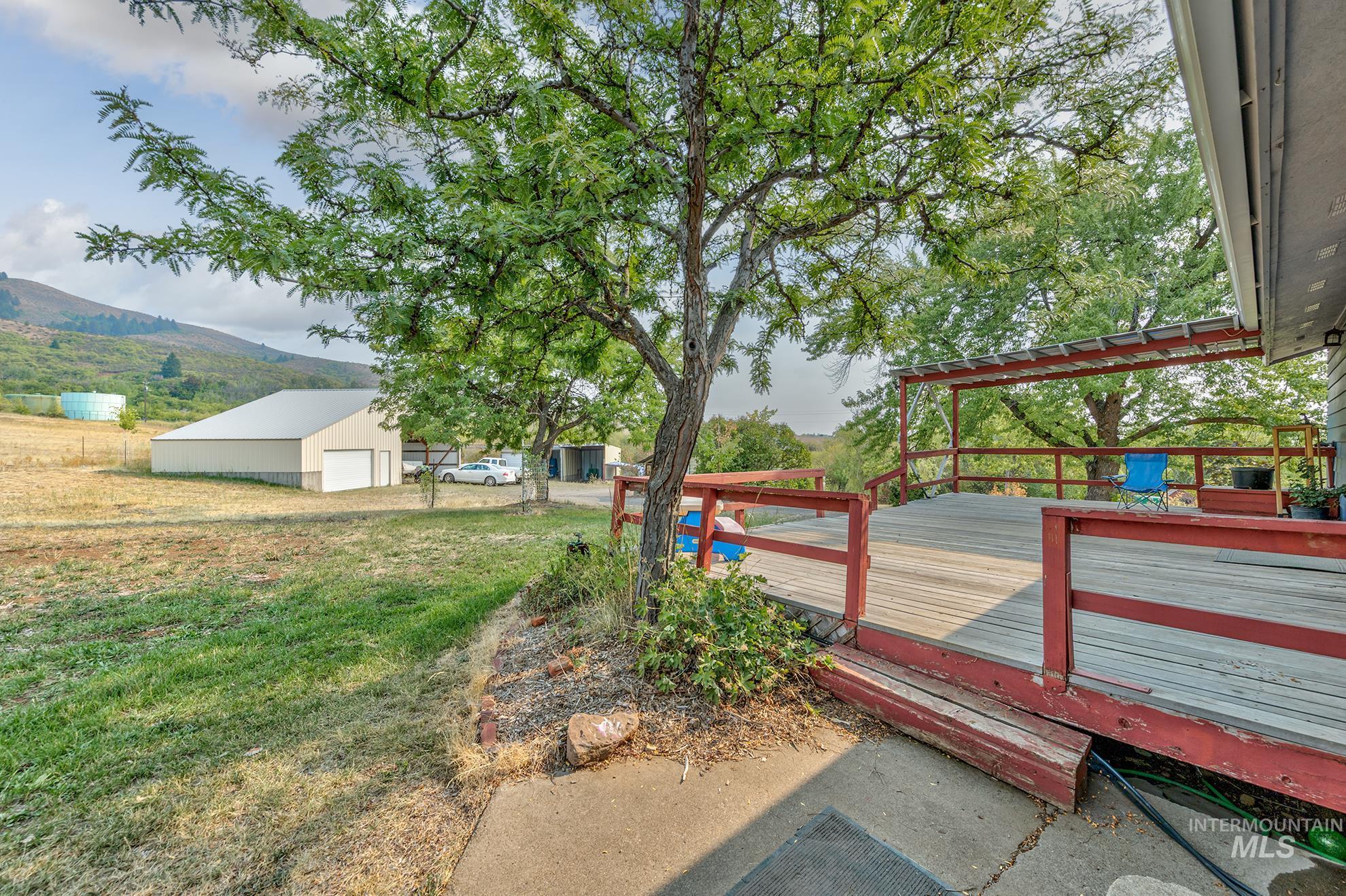 View of grassy yard featuring a deck with mountain view, an outbuilding, and a garage