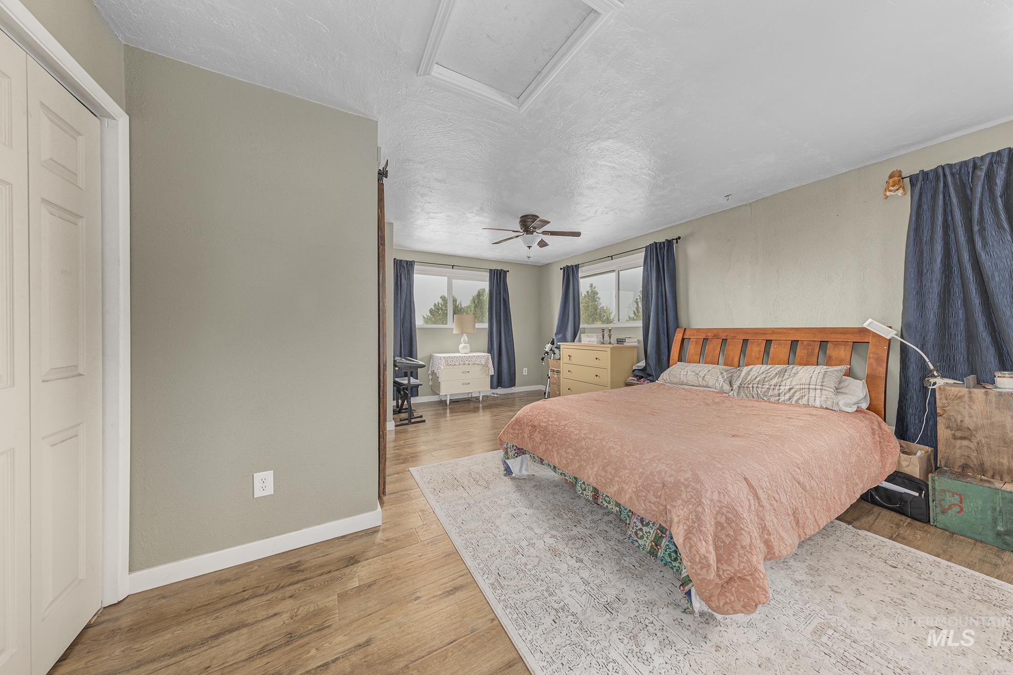 Bedroom with light wood-style floors, a textured ceiling, and ceiling fan