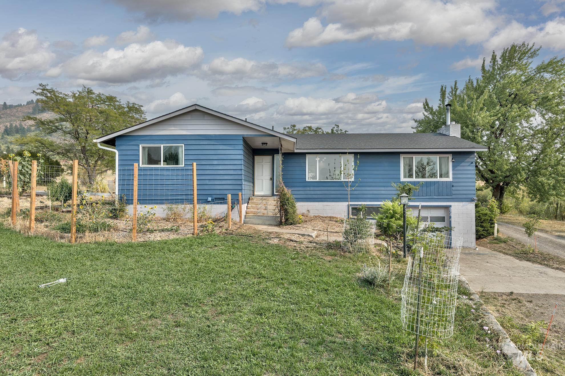 Ranch-style home featuring a chimney, driveway, a front lawn, and a garage