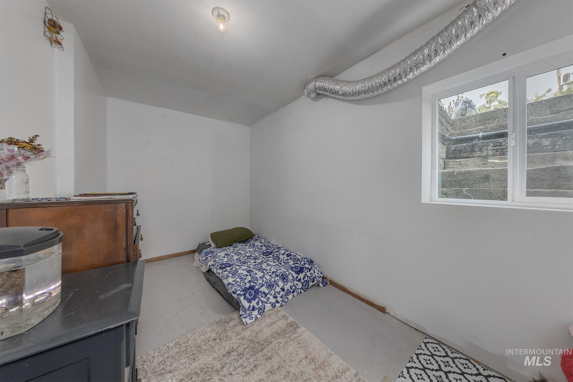 Bedroom featuring concrete flooring and baseboards