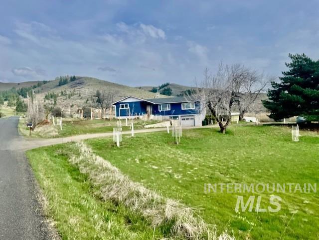 Rear view of house featuring a mountain view, a view of countryside, a yard, and driveway
