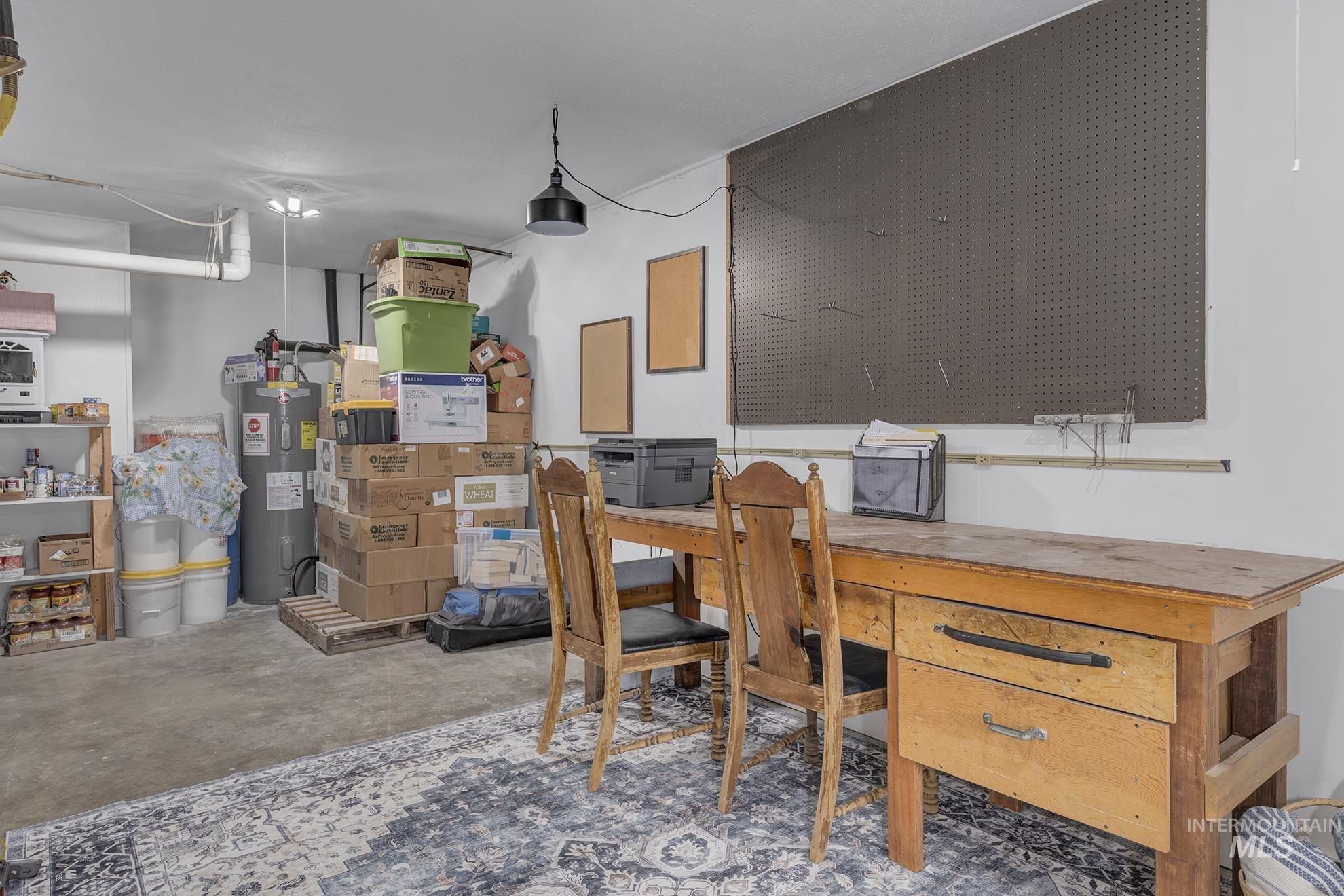 Office space featuring unfinished concrete flooring and electric water heater