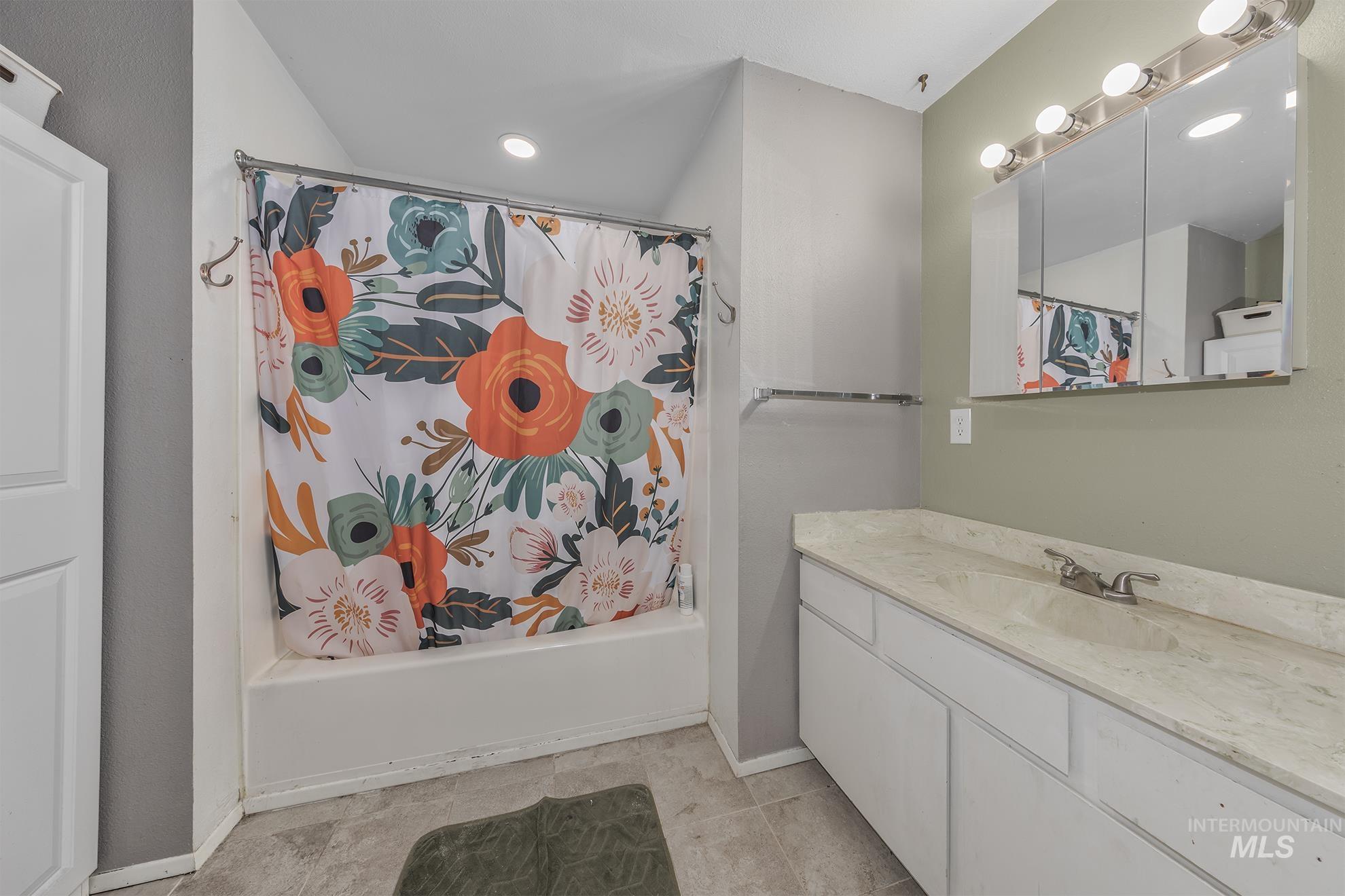 Bathroom with shower / bath combo with shower curtain, vanity, and light tile patterned floors