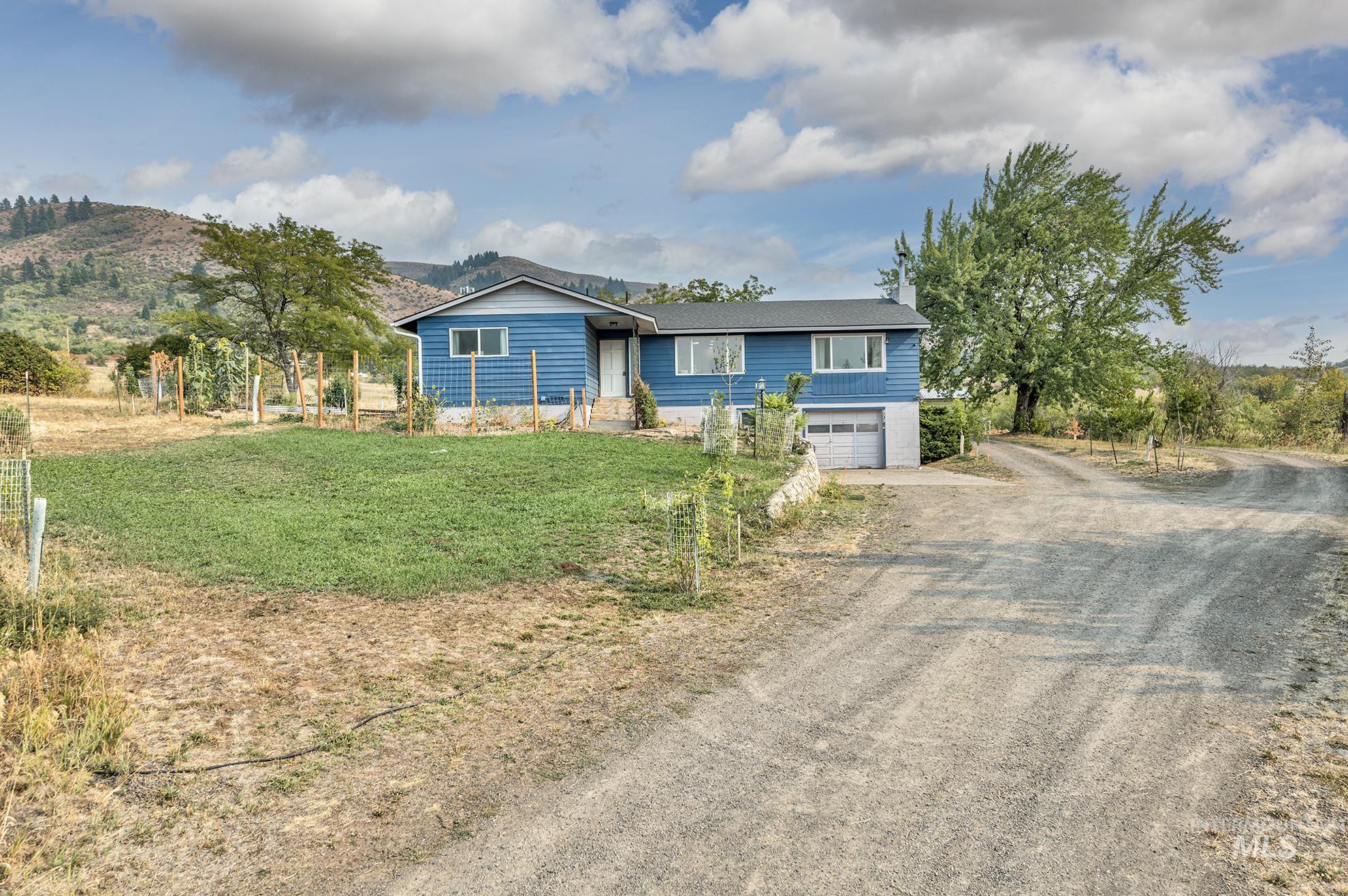 Single story home featuring dirt driveway, an attached garage, and a front yard