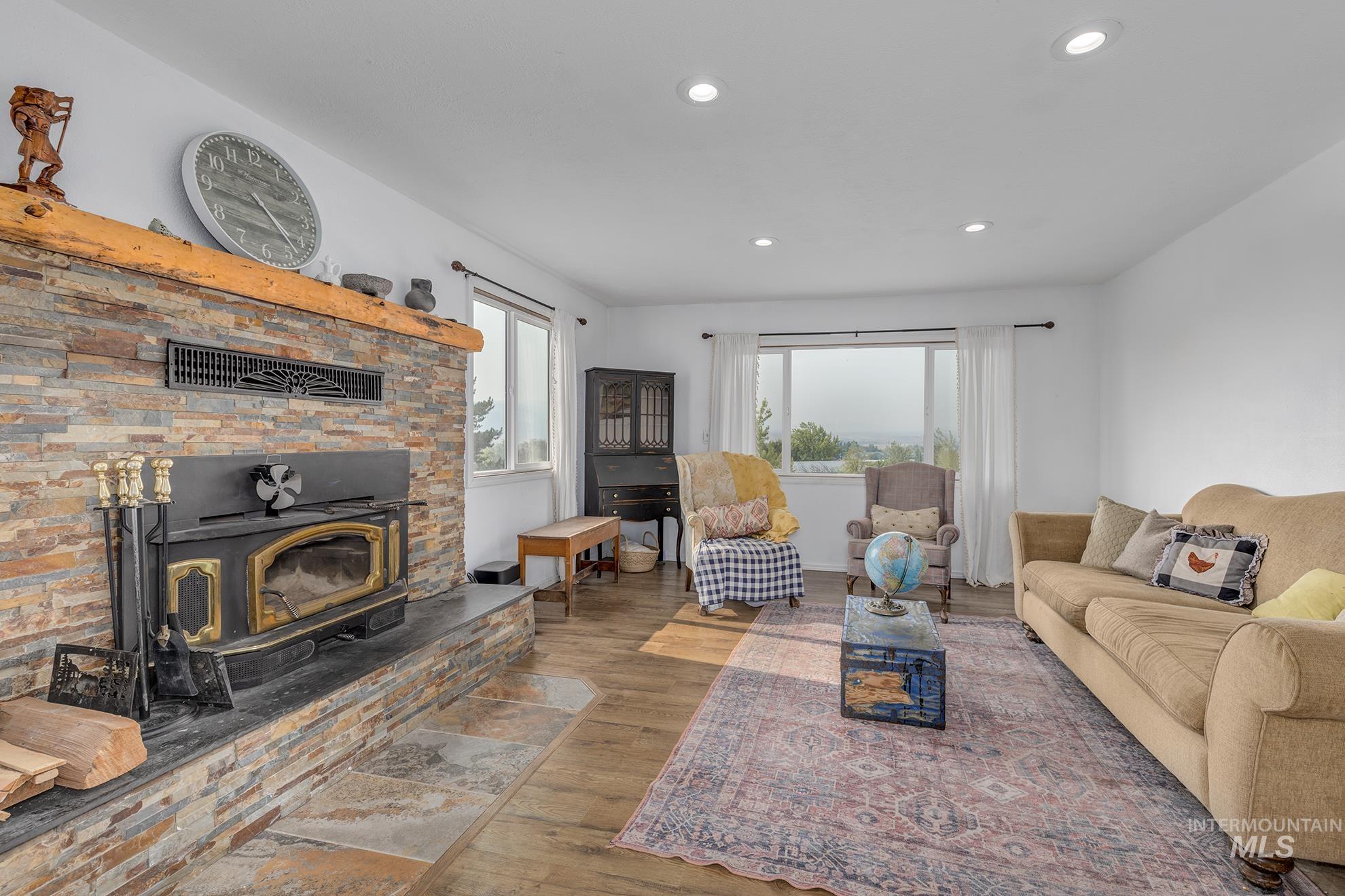 Living room with wood finished floors, a wood stove, and recessed lighting