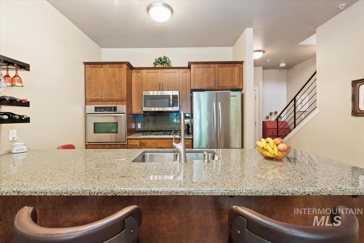Kitchen with a kitchen bar, light stone counters, and stainless steel appliances