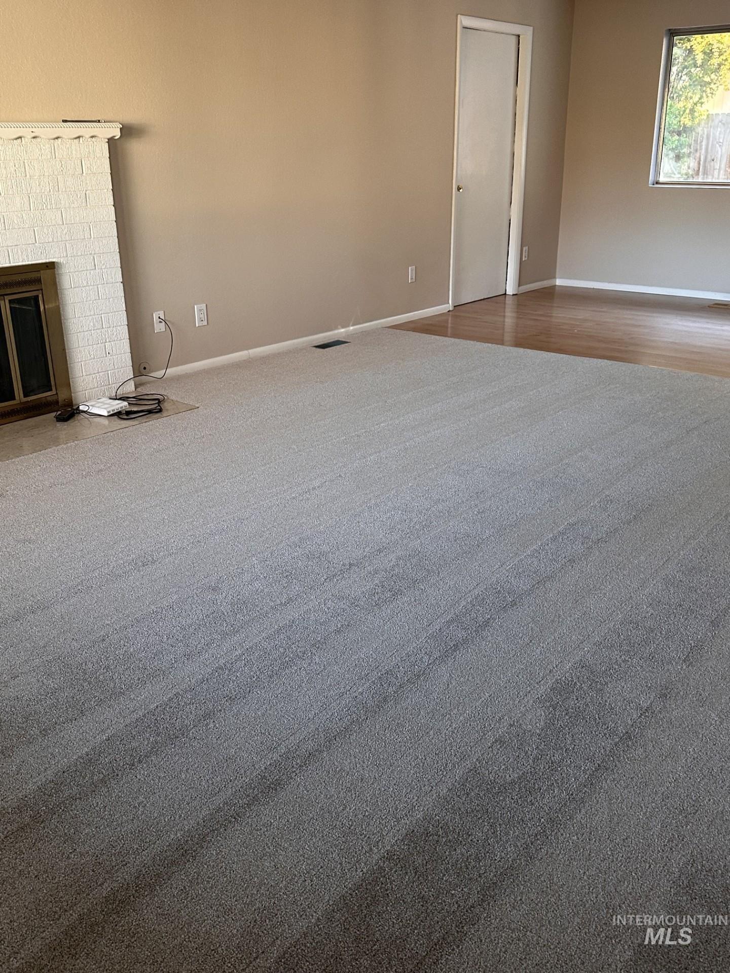 Unfurnished living room featuring baseboards and wood finished floors