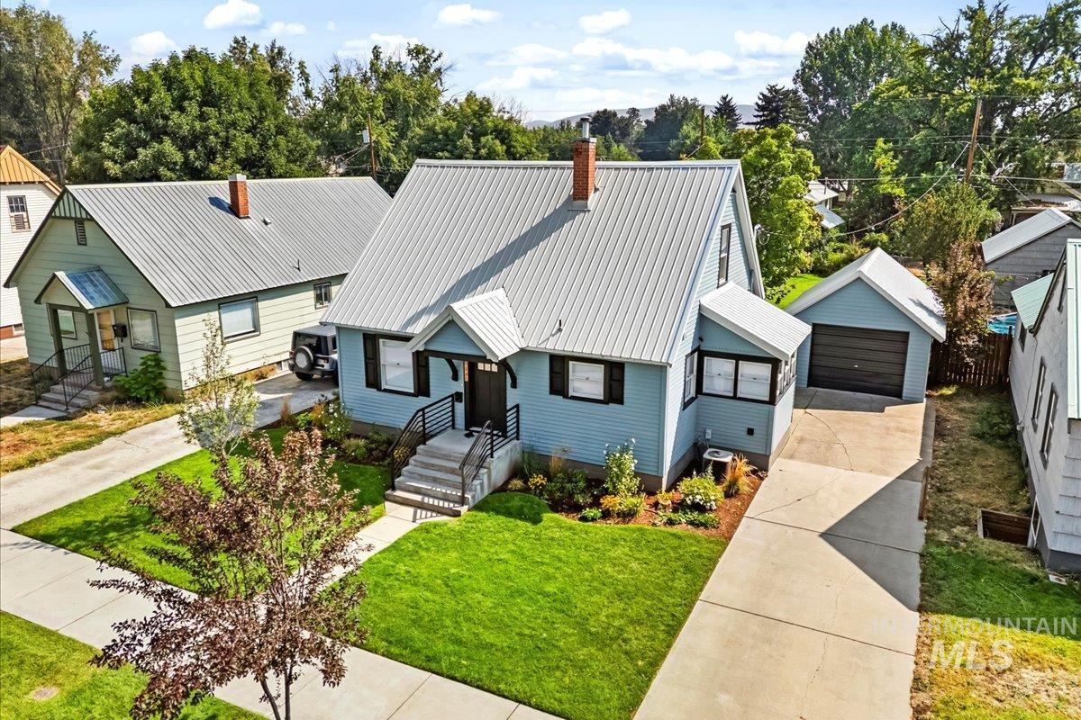 View of front facade with a detached garage, an outdoor structure, a metal roof, a chimney, and a front yard