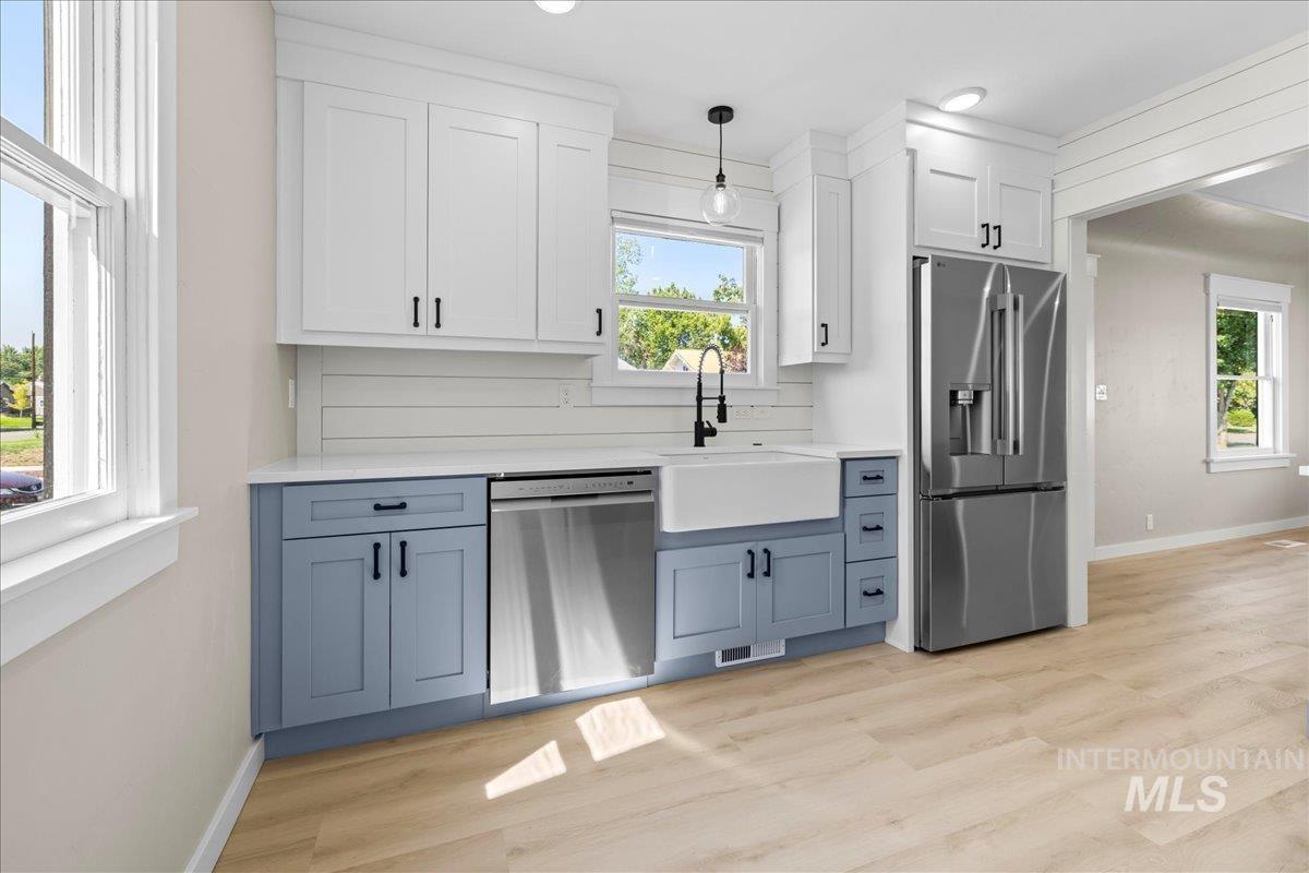 Kitchen with white cabinets, stainless steel appliances, blue cabinets, hanging light fixtures, and recessed lighting