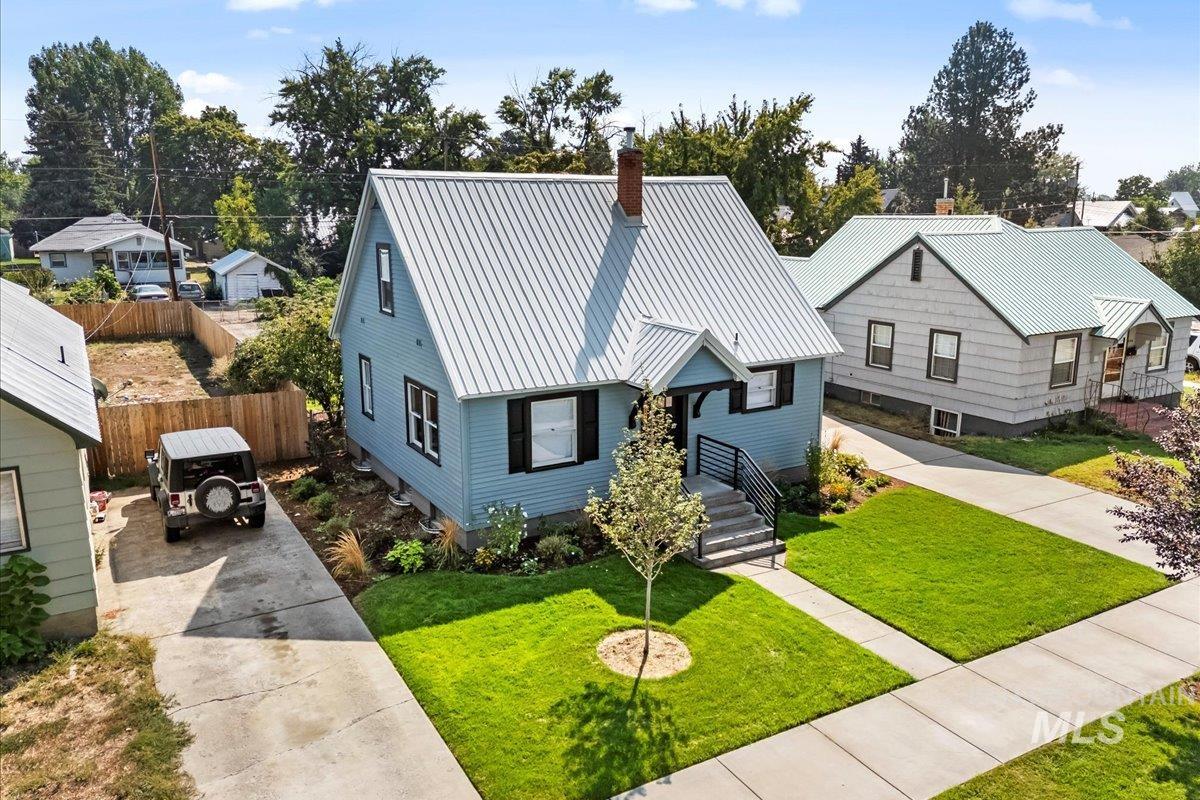 View of front of property with a metal roof, concrete driveway, and a chimney