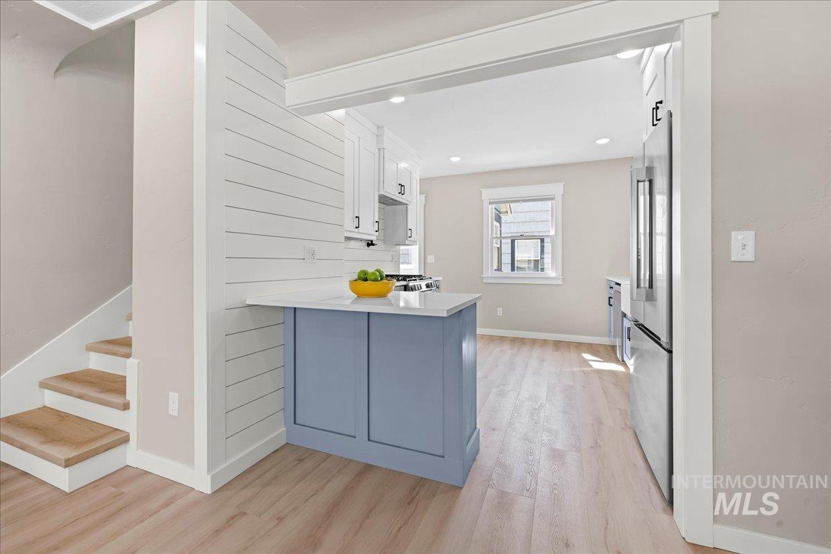 Kitchen with white cabinets, a peninsula, light wood finished floors, and high end refrigerator