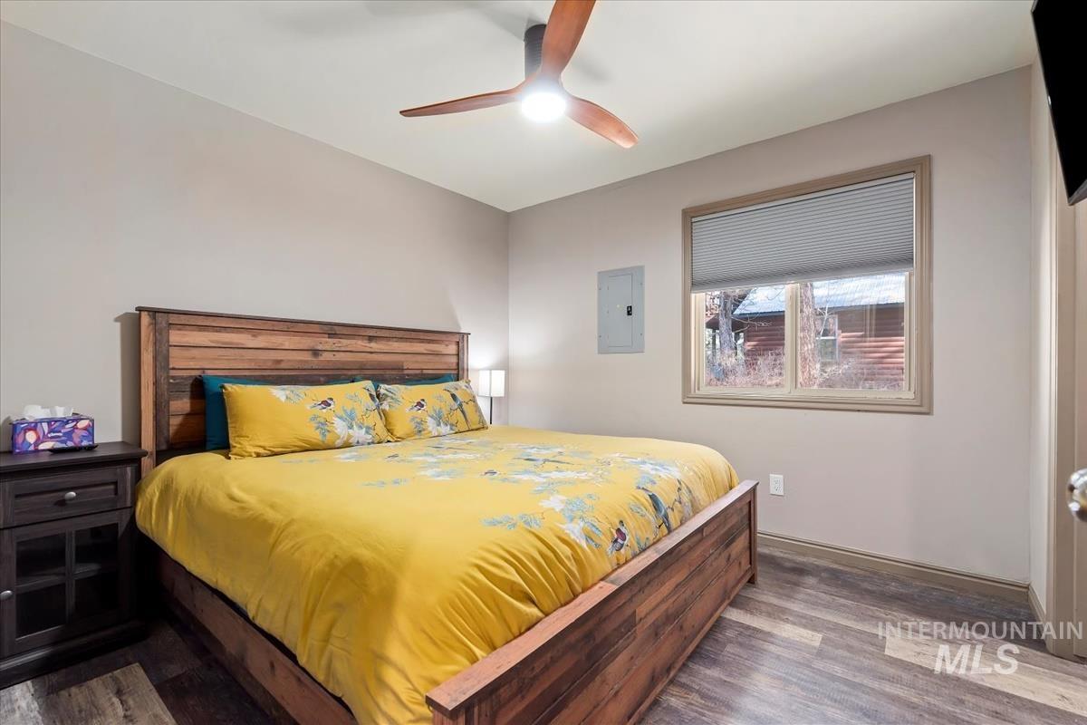 Bedroom featuring dark wood finished floors, electric panel, and ceiling fan