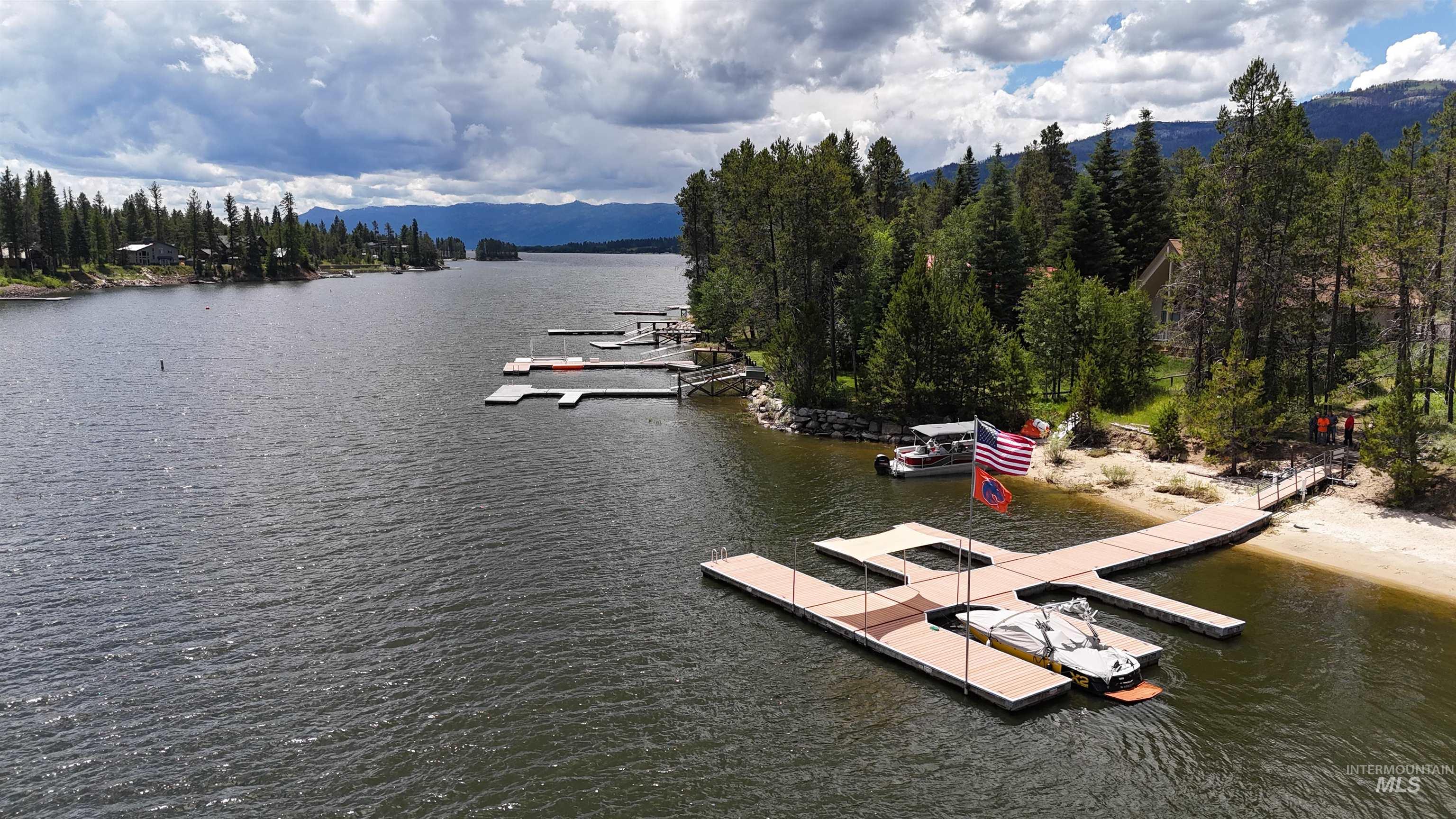 Waterfront property featuring a private sandy beach, multiple private docks, and mature pine trees