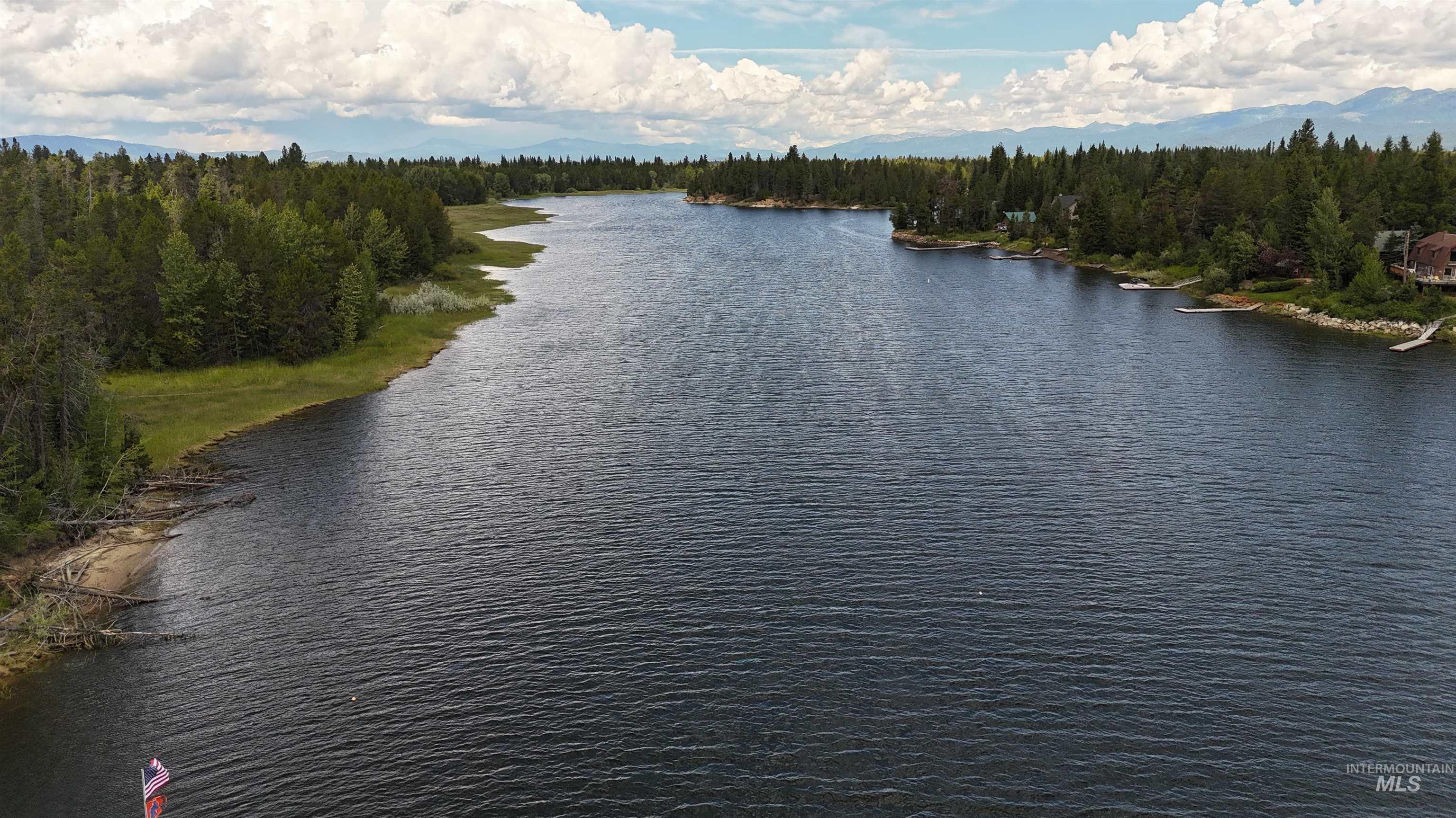 Expansive lakefront property featuring a forested shoreline, a private dock, and distant mountain ranges
