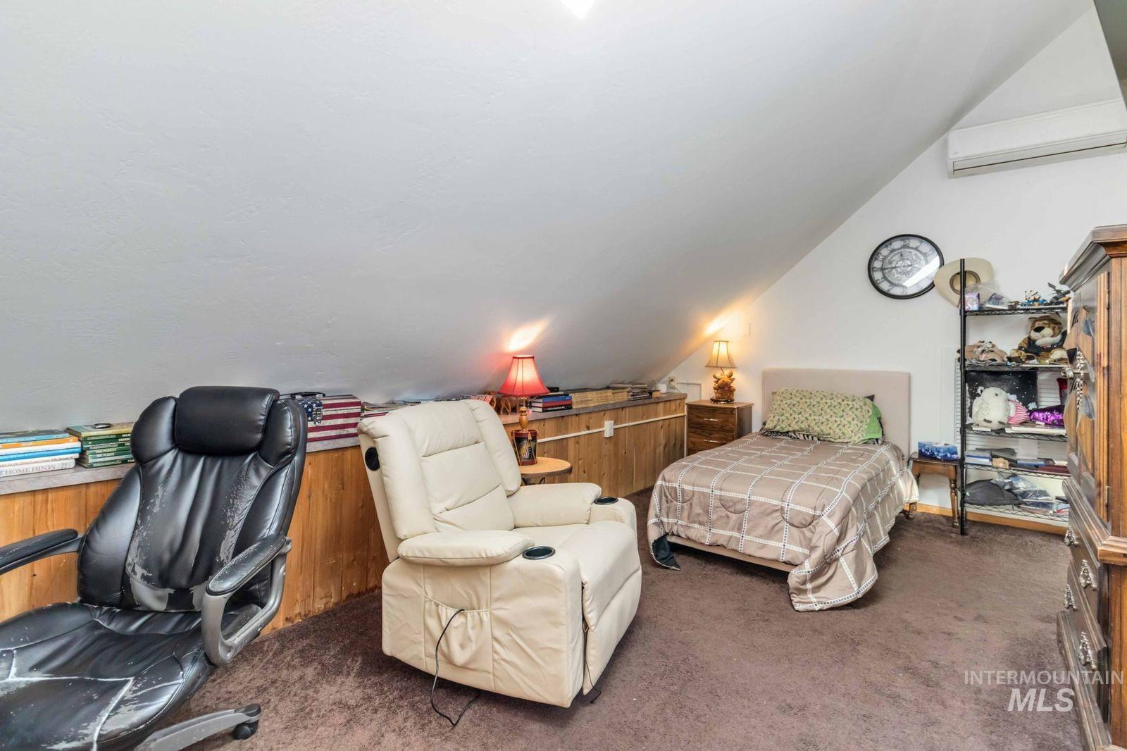Bedroom featuring carpet flooring, lofted ceiling, an AC wall unit, and a desk