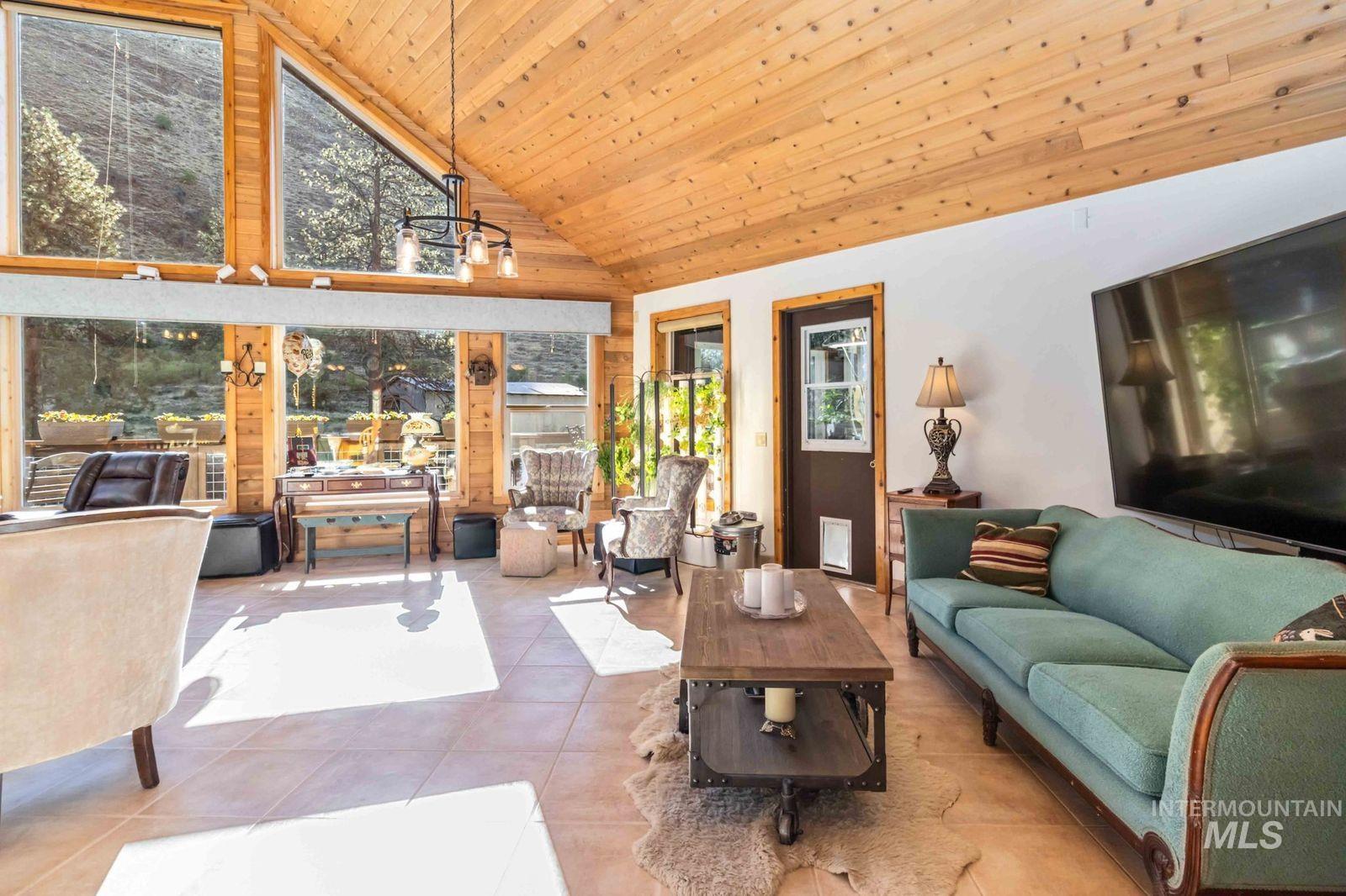 Tiled living room with wood ceiling, high vaulted ceiling, and a chandelier
