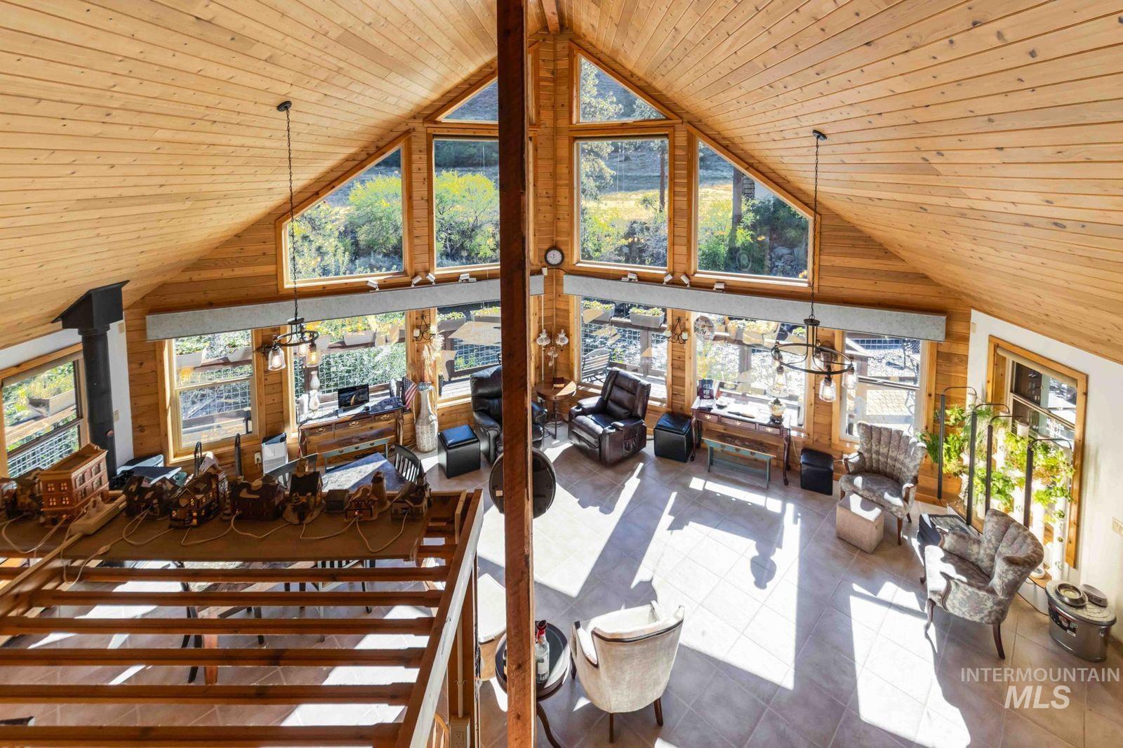 Tiled living room featuring wooden ceiling, wood walls, high vaulted ceiling, and a wood stove