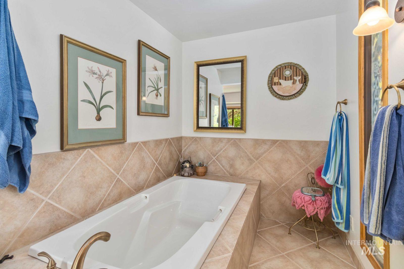 Full bathroom with tile patterned flooring, a bath, and tile walls