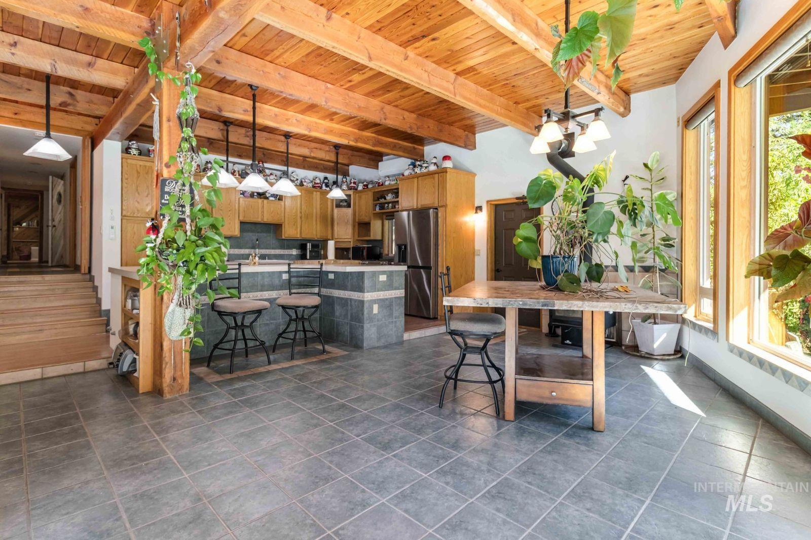 Dining area featuring a wood ceiling with exposed beams and dark tile patterned flooring