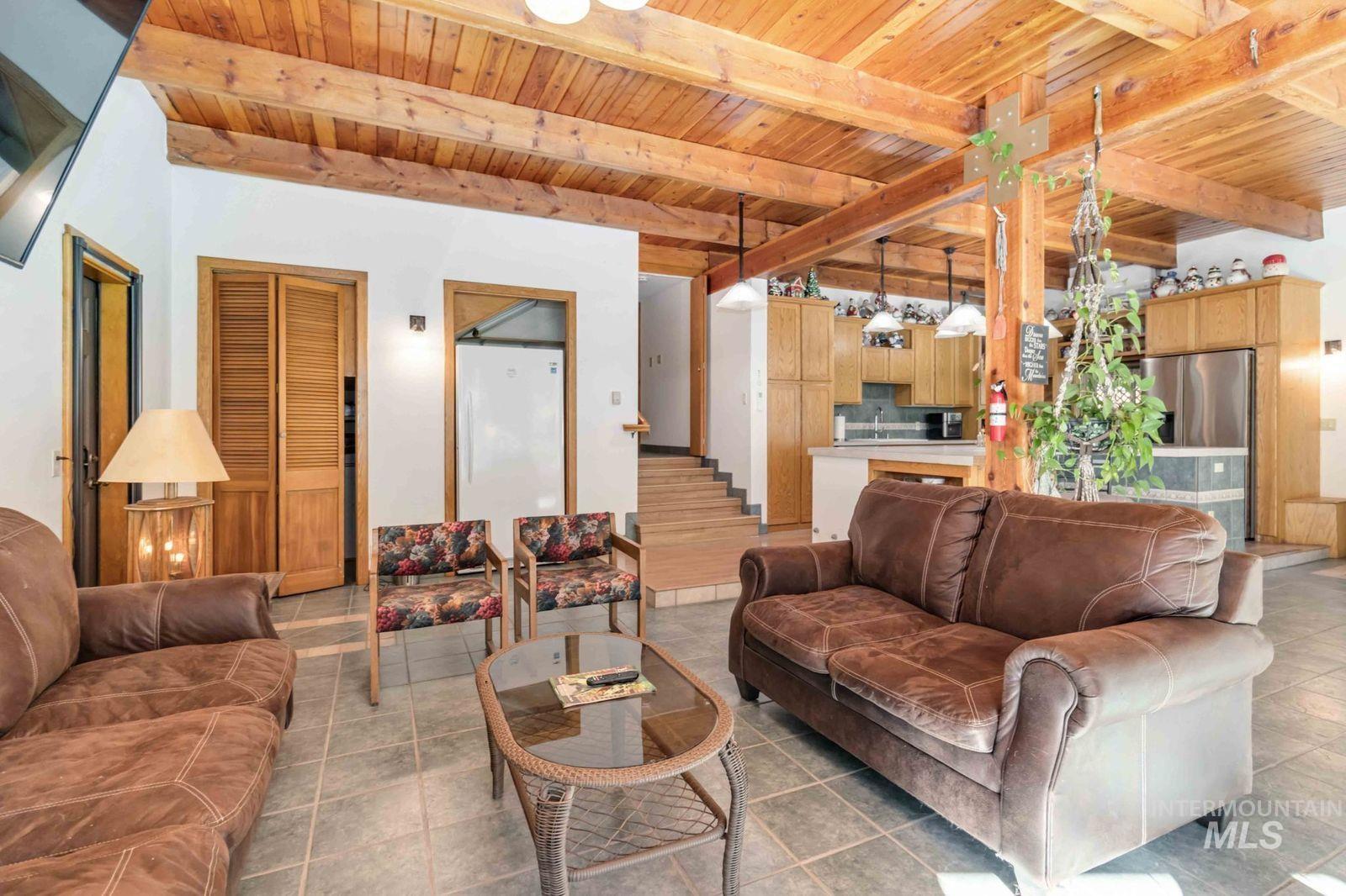 Living area featuring a wood ceiling with exposed beams and light tile patterned floors