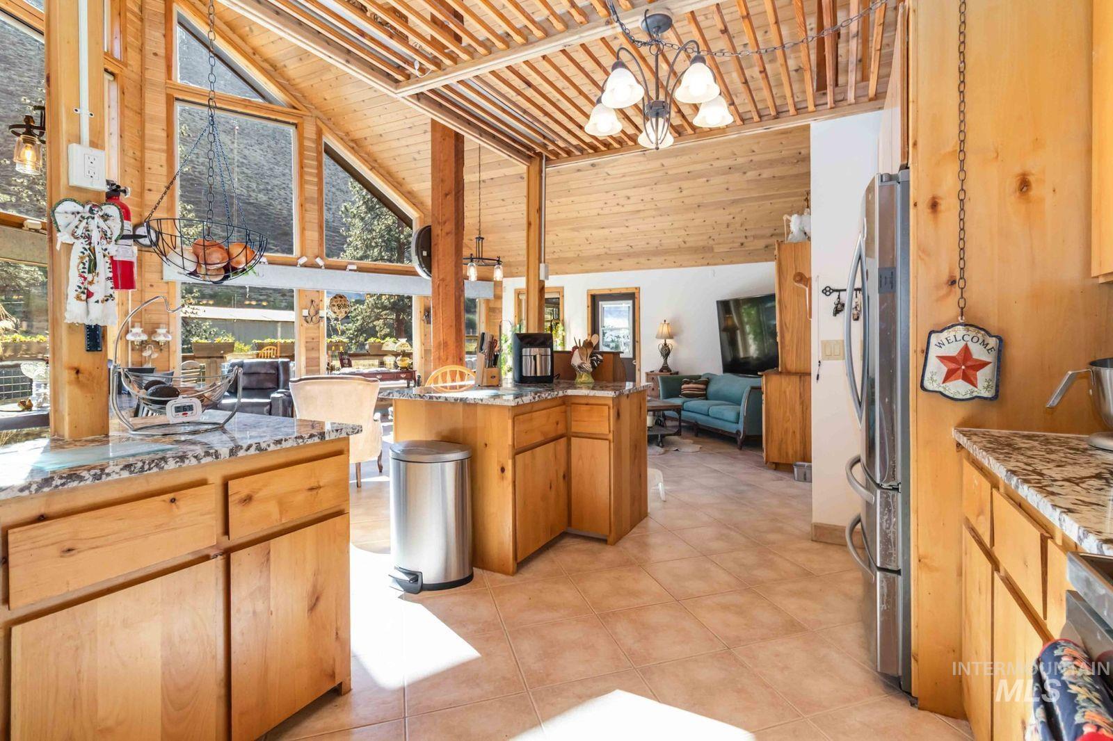 Kitchen featuring light stone countertops, pendant lighting, open floor plan, a chandelier, and freestanding refrigerator