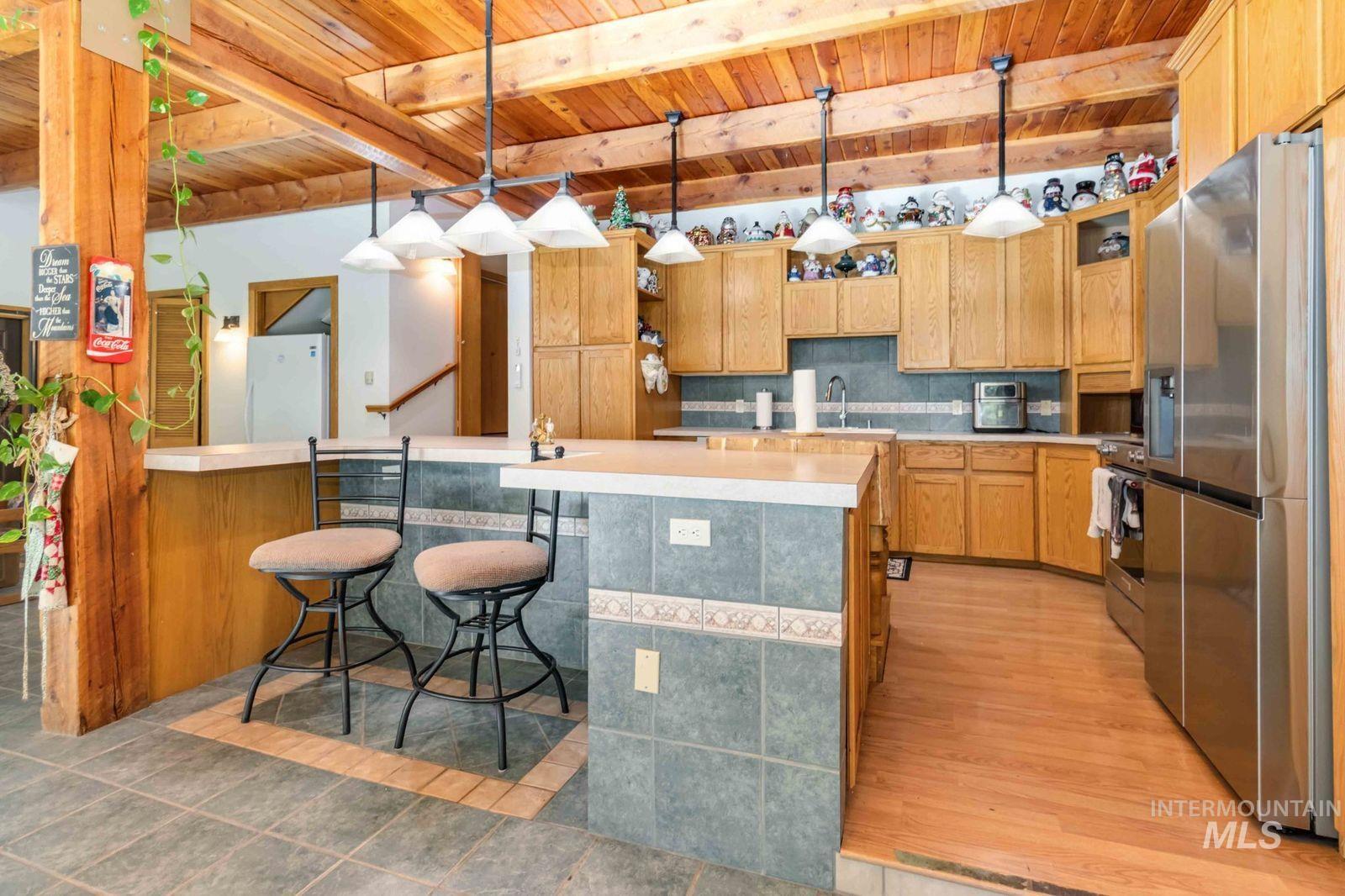 Kitchen featuring a kitchen breakfast bar, backsplash, pendant lighting, light countertops, and appliances with stainless steel finishes