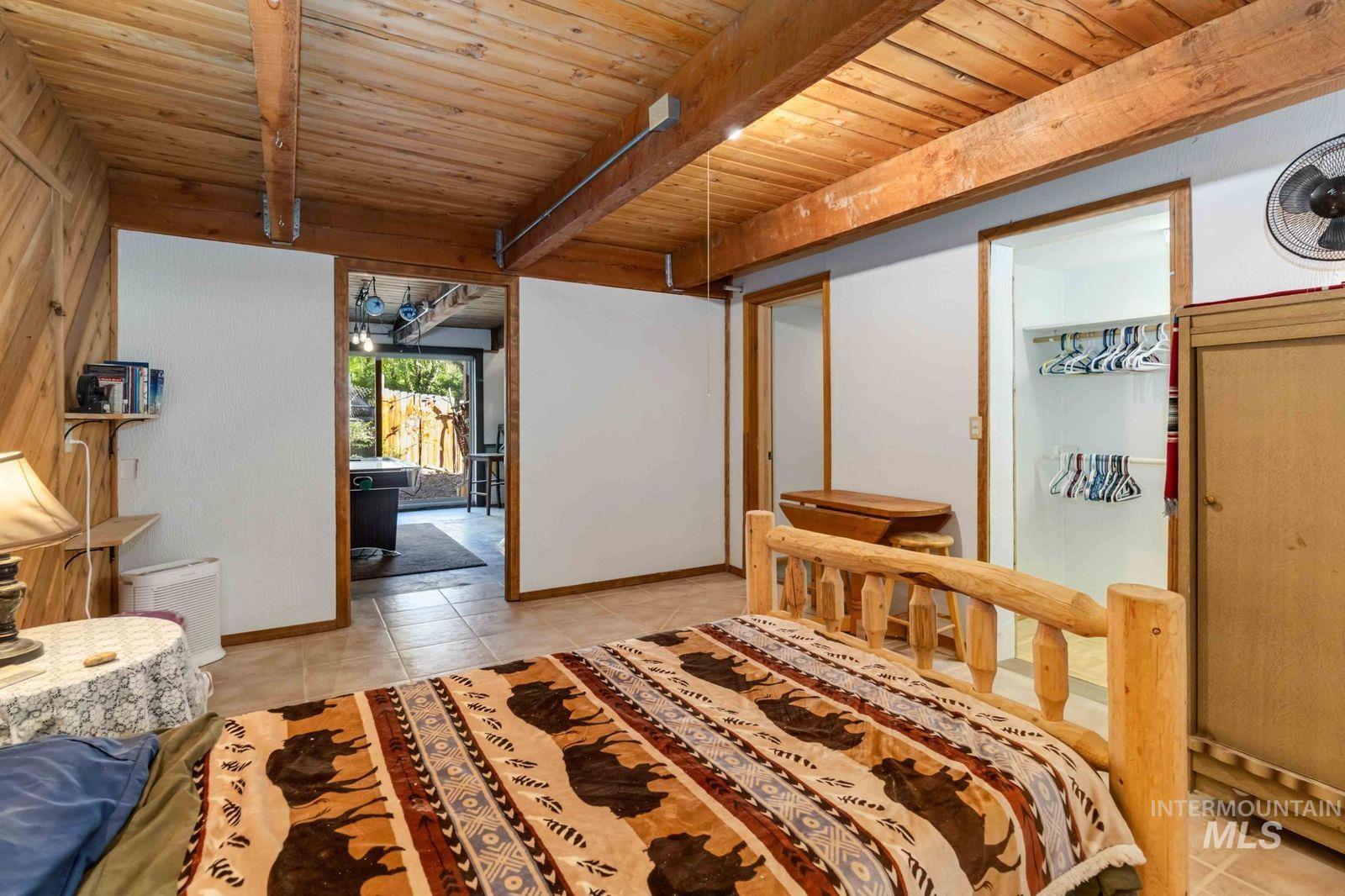 Bedroom featuring light tile patterned flooring and a wood ceiling with exposed beams