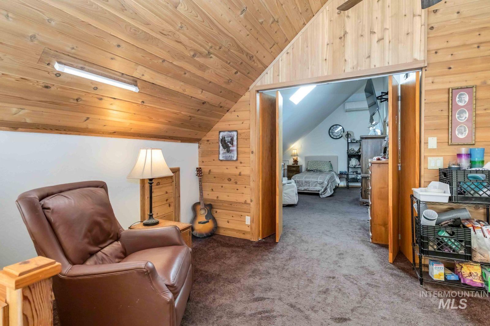 Sitting room with lofted ceiling, wood walls, carpet flooring, and wood ceiling
