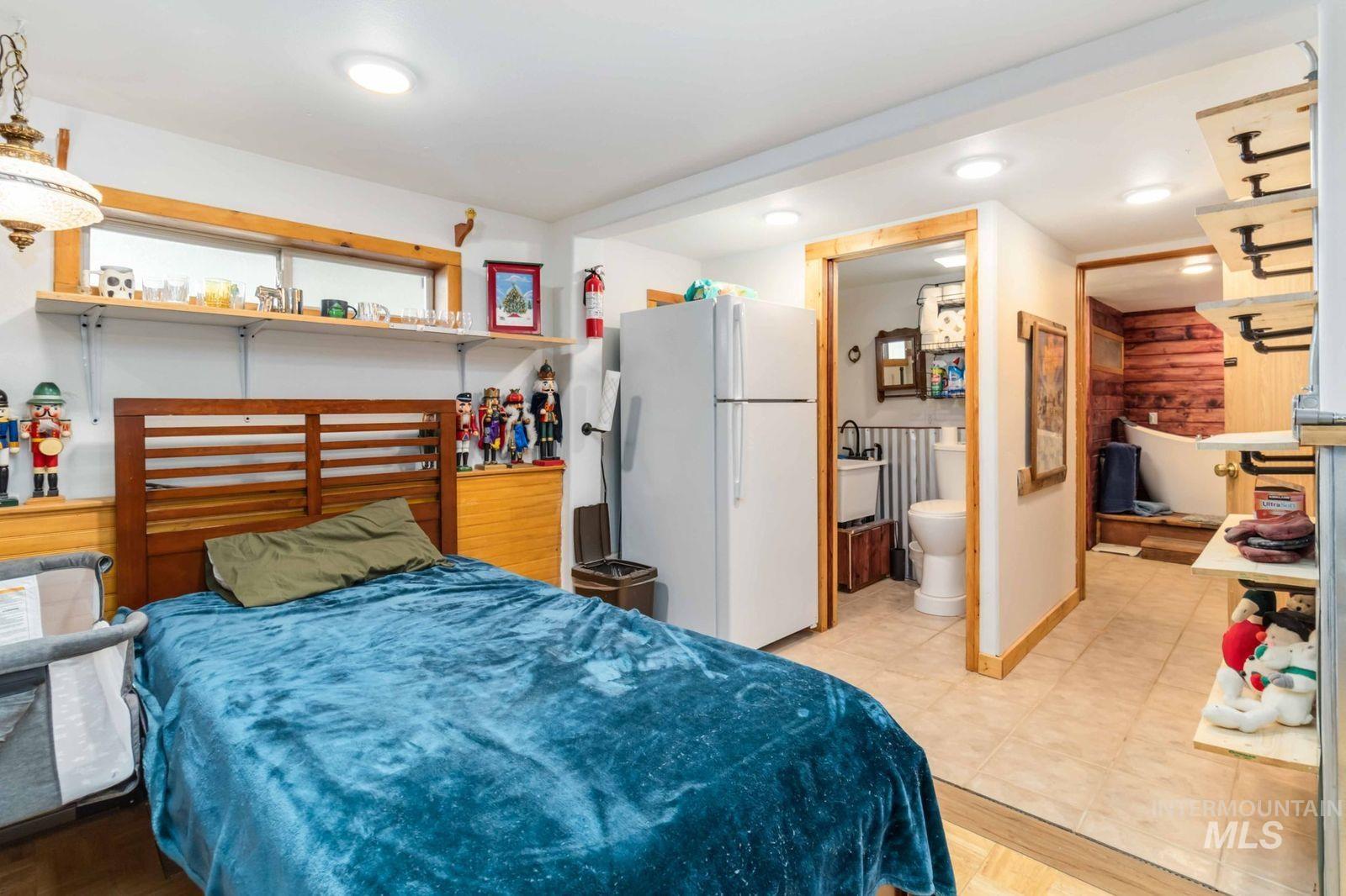 Bedroom featuring freestanding refrigerator, recessed lighting, ensuite bath, and a closet