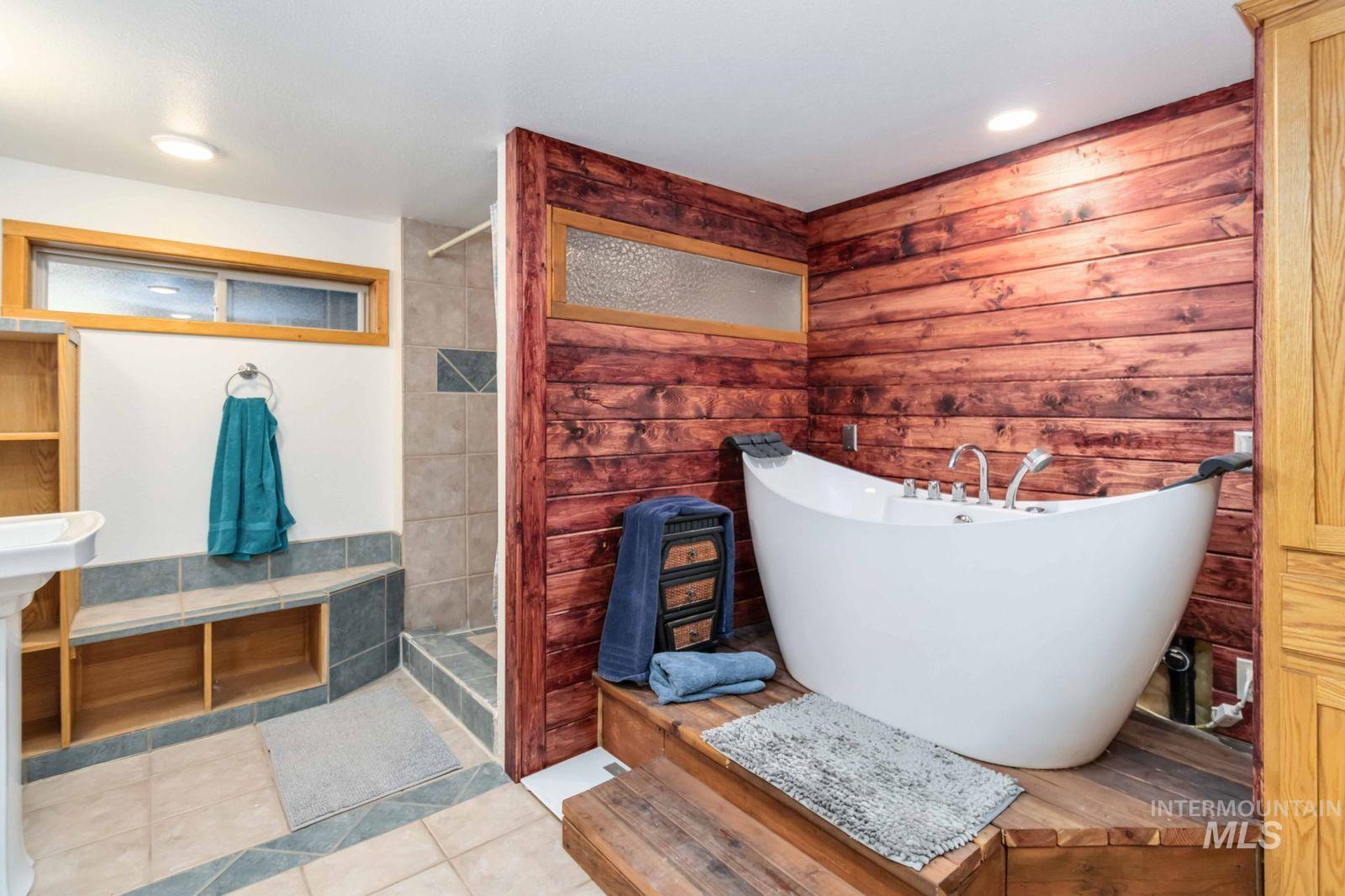 Full bathroom featuring a freestanding bath, tile patterned floors, a tile shower, recessed lighting, and tile walls