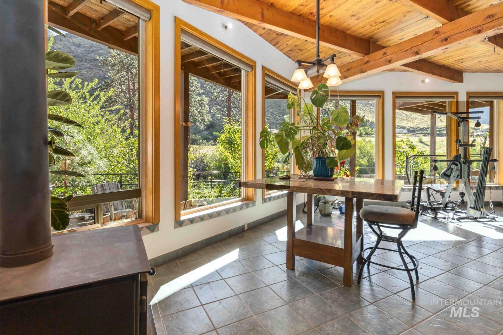 Sunroom / solarium with a wood ceiling with exposed beams and tile patterned flooring