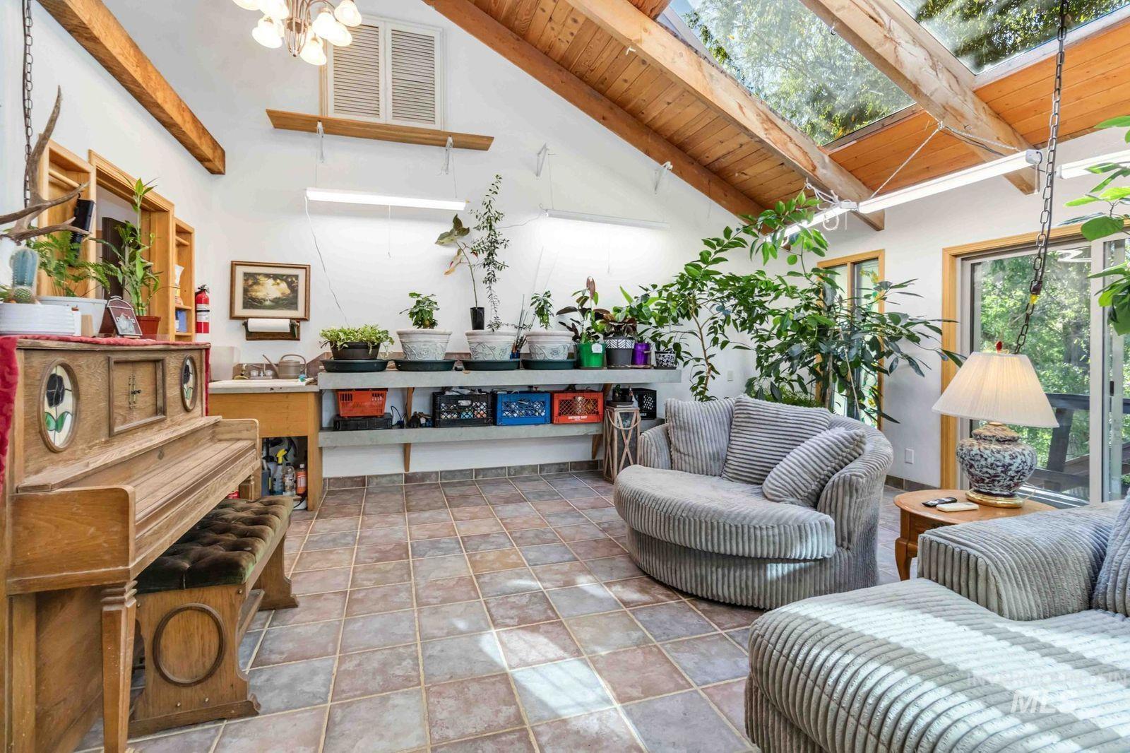 Tiled living room with a wood ceiling with exposed beams, high vaulted ceiling, and a skylight