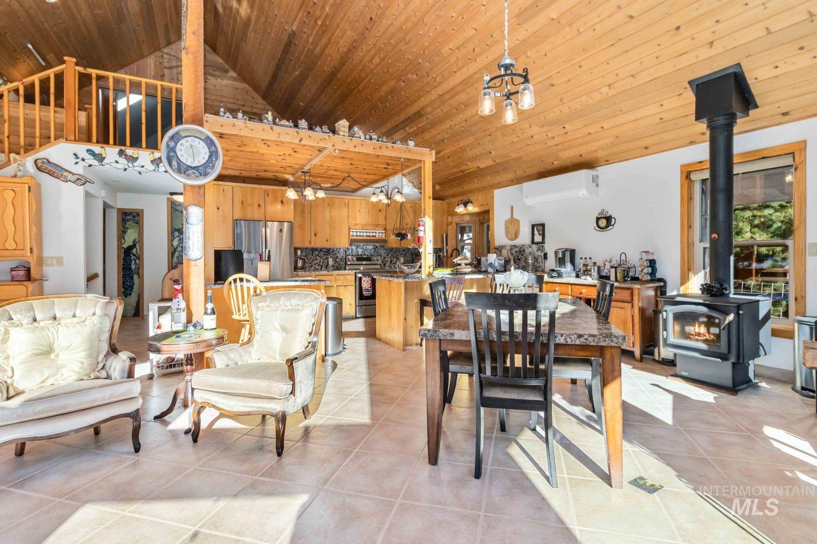 Dining room with a wood stove, light tile patterned floors, a chandelier, vaulted ceiling, and an AC wall unit