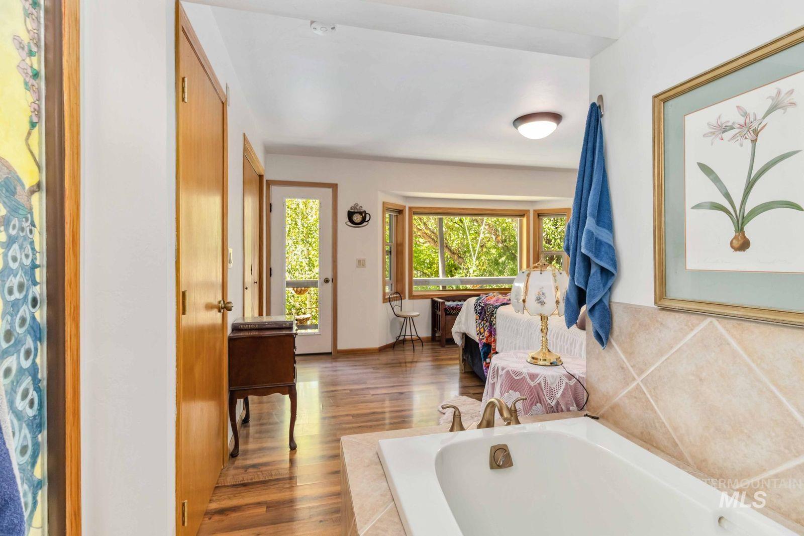 Full bathroom featuring wood finished floors, a bath, and a shower with shower curtain