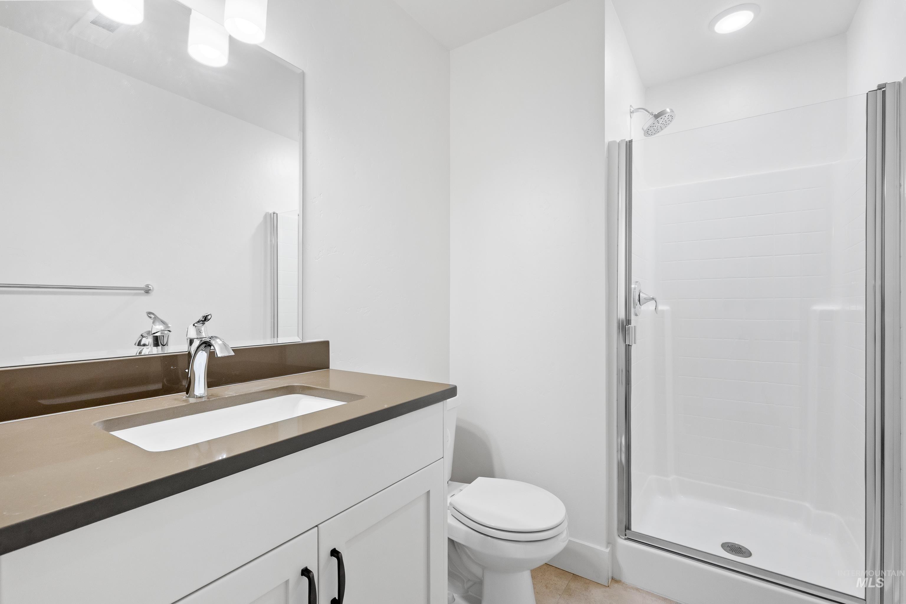 Full bathroom featuring vanity, a stall shower, and light tile patterned flooring