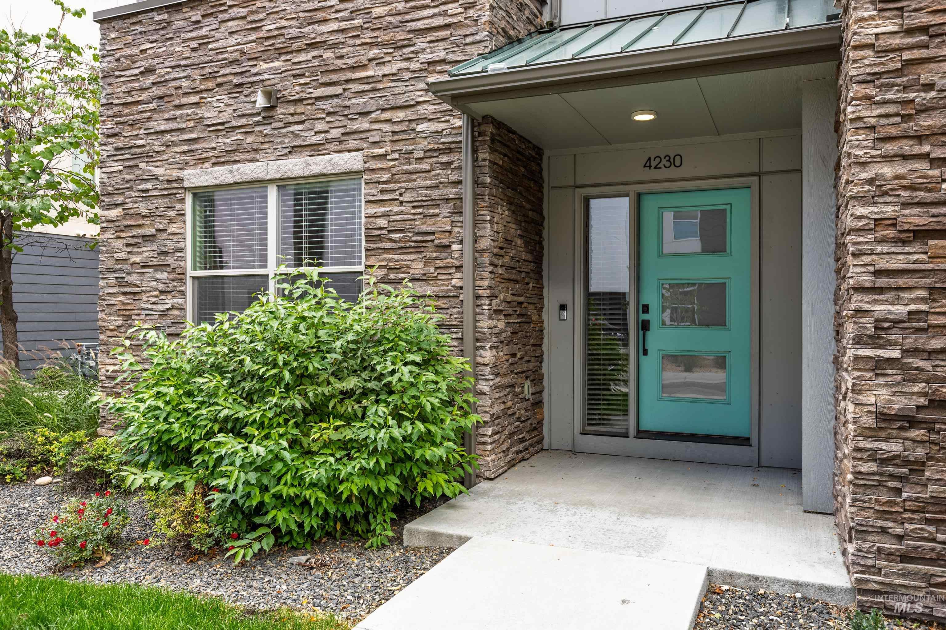 Entrance to property with stone siding, a standing seam roof, and a metal roof