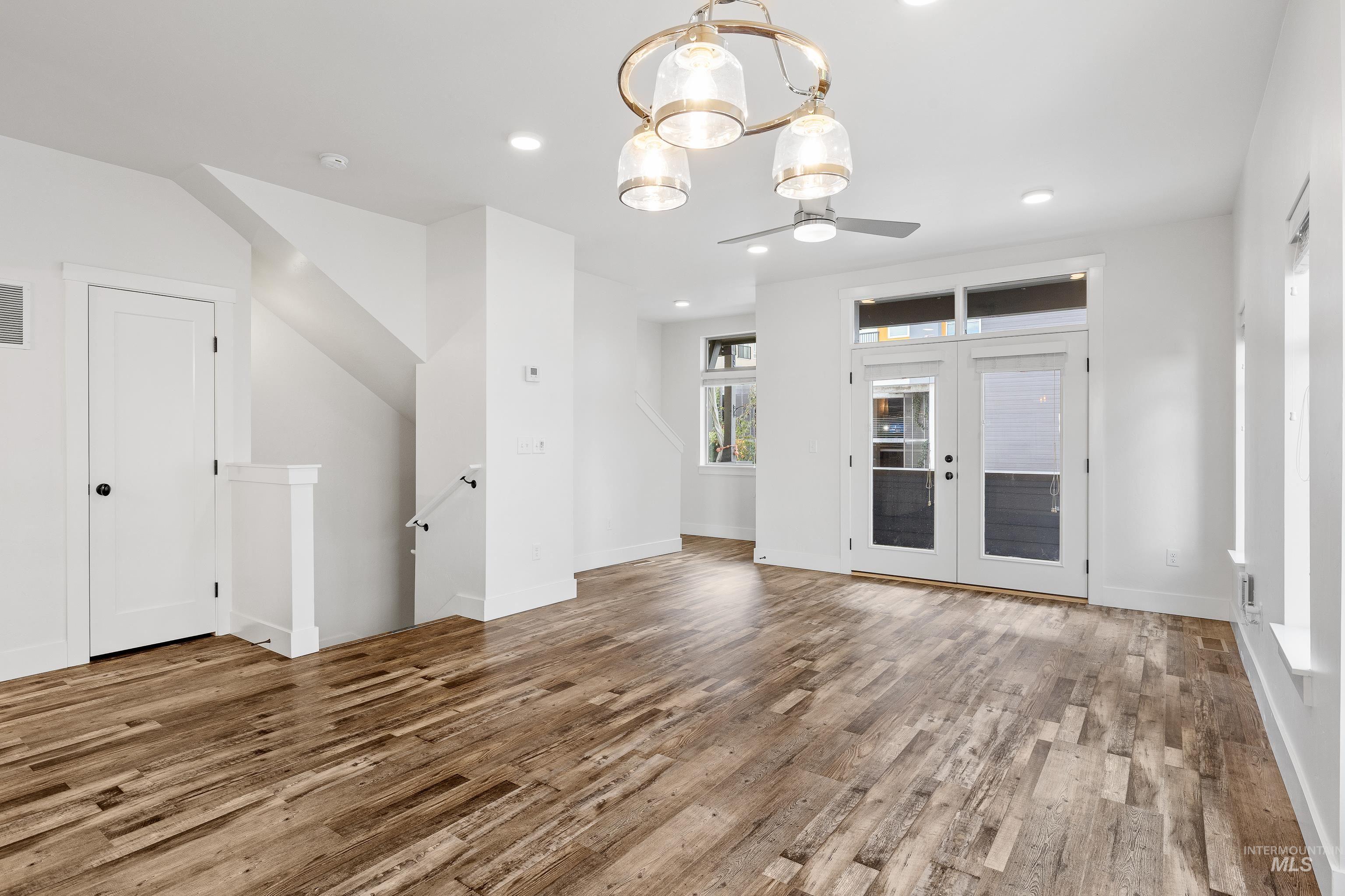 Unfurnished living room featuring recessed lighting, light wood-type flooring, a chandelier, french doors, and a ceiling fan