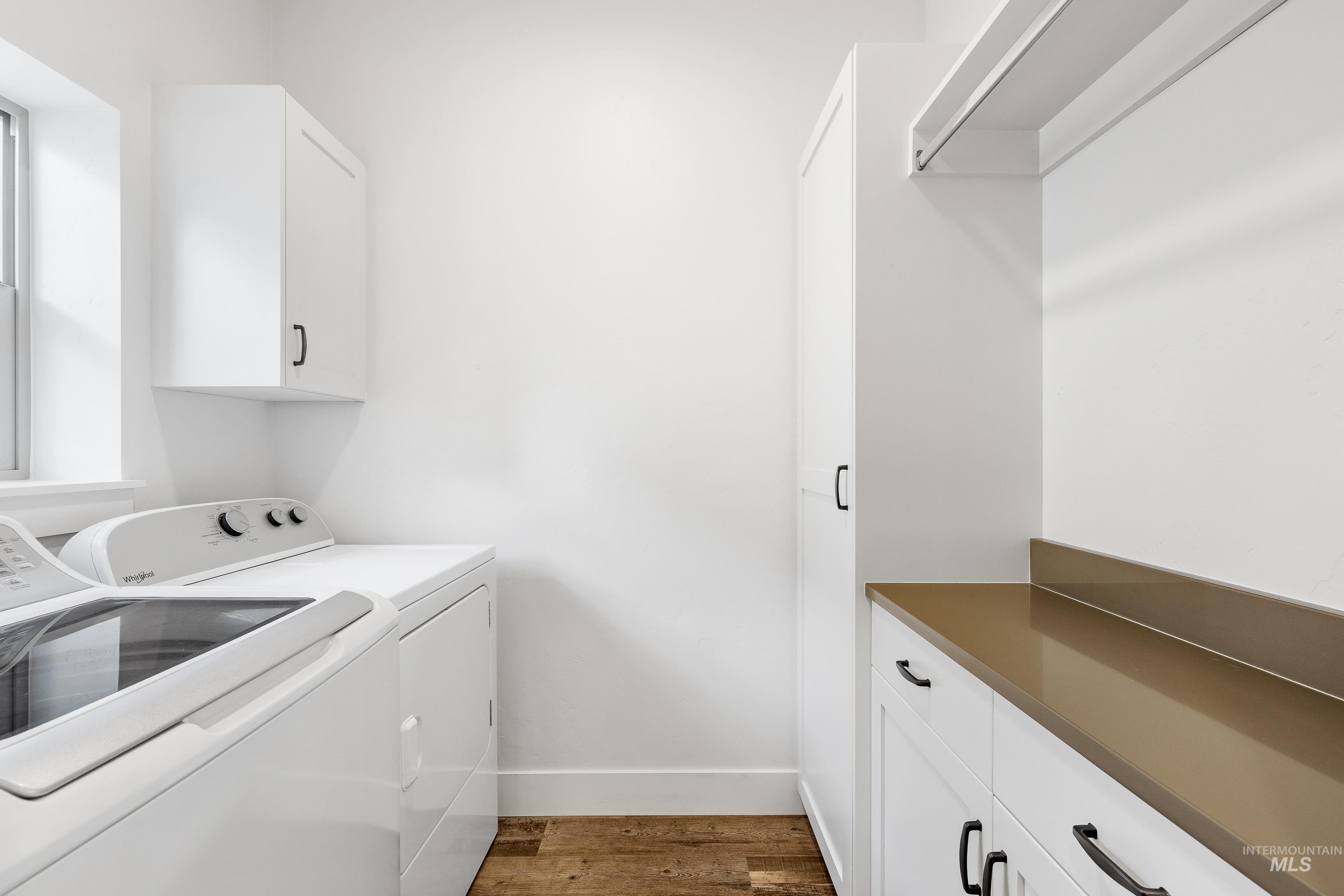 Laundry area with dark wood-style floors, cabinet space, and washing machine and clothes dryer