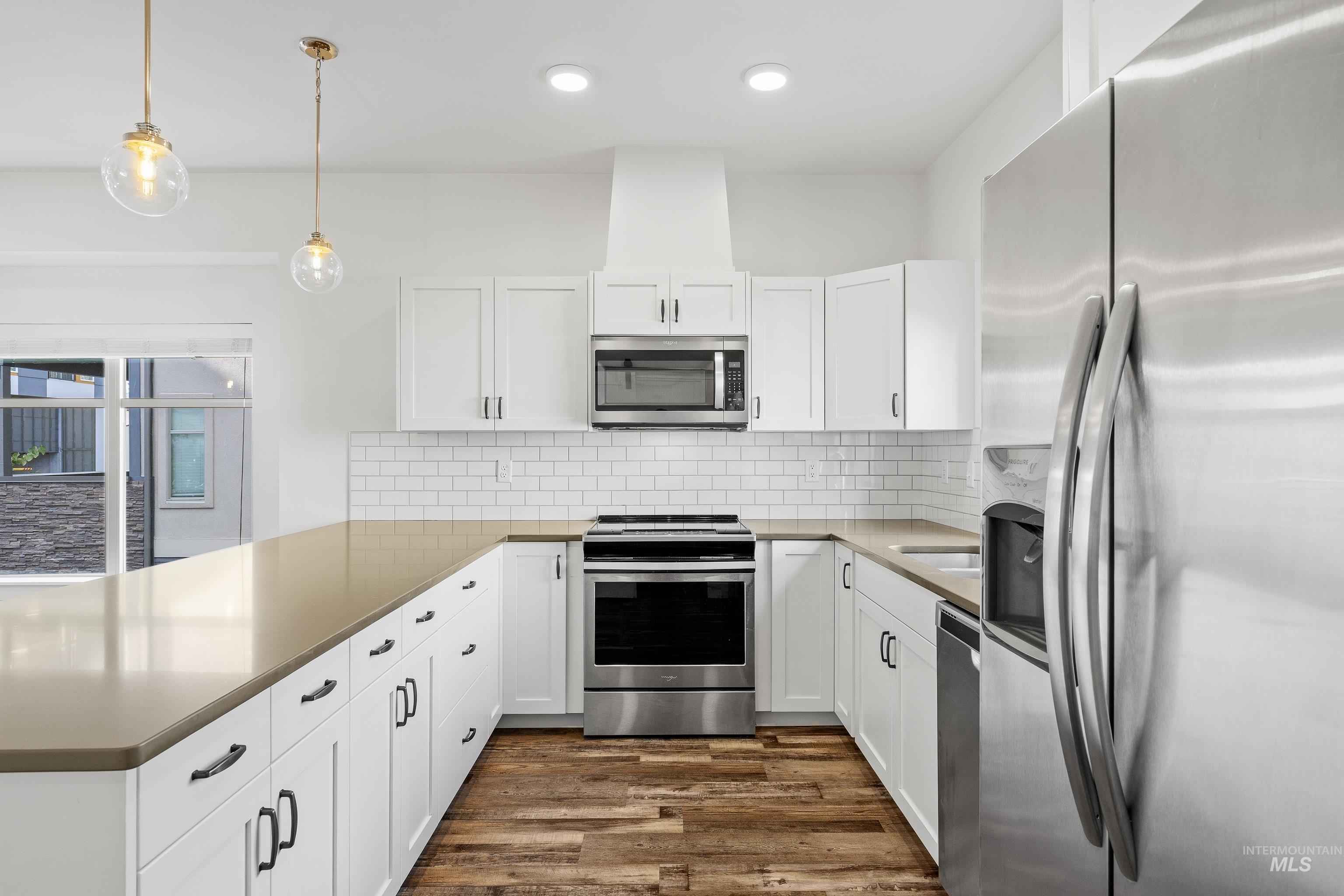 Kitchen featuring stainless steel appliances, white cabinets, pendant lighting, and recessed lighting