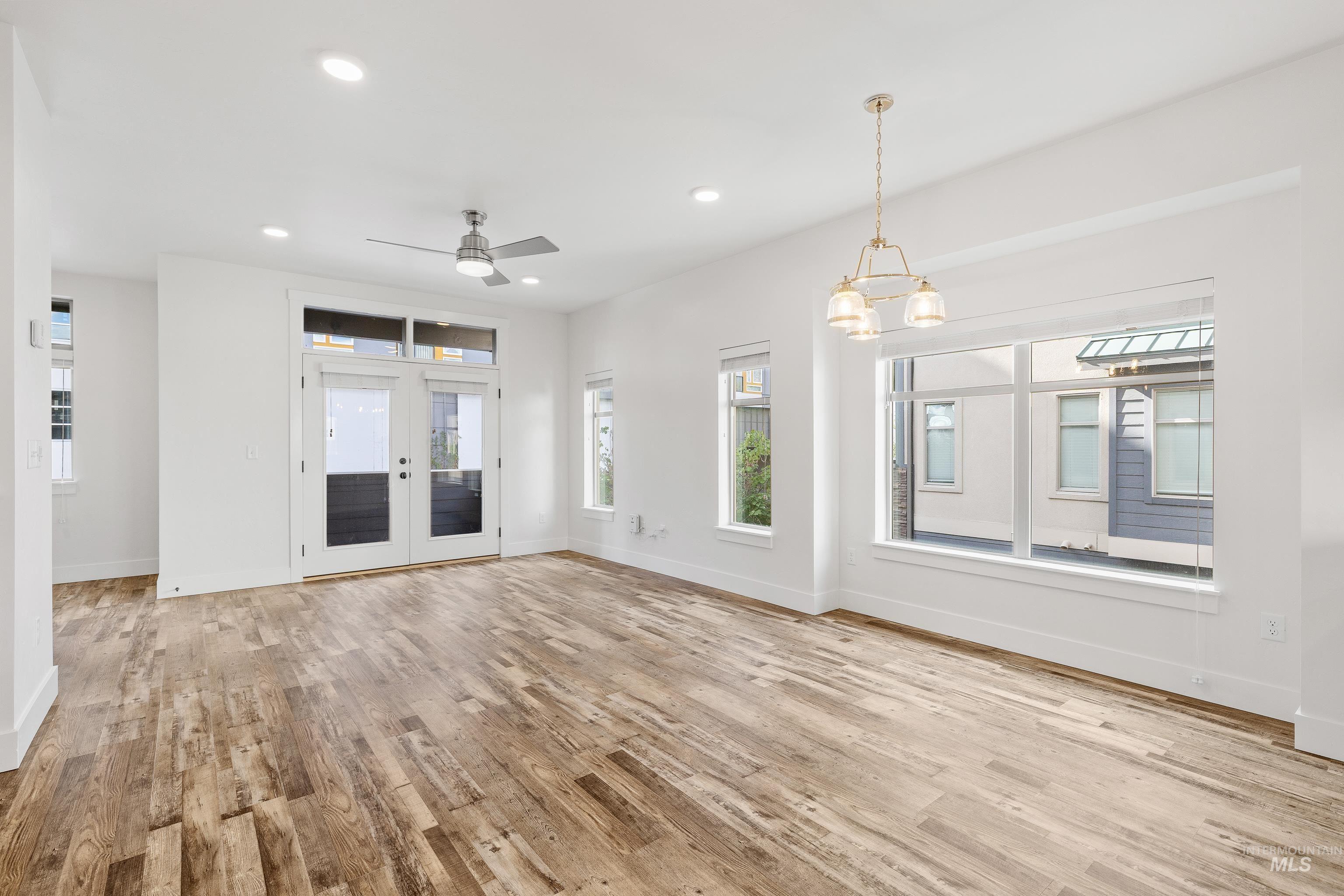 Unfurnished living room with recessed lighting, french doors, light wood-style floors, a ceiling fan, and a chandelier