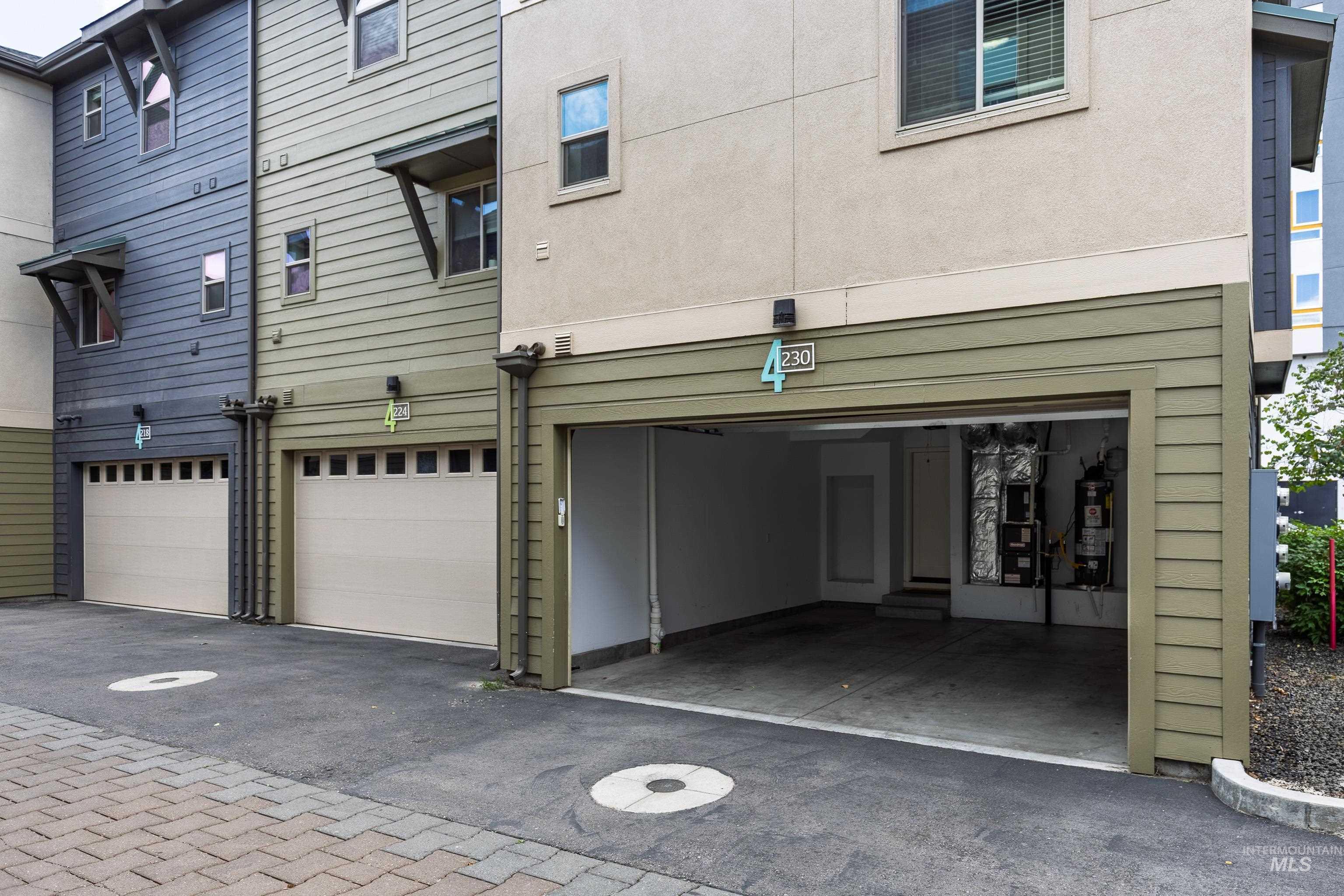 Rear view of property featuring a garage, gas water heater, and driveway
