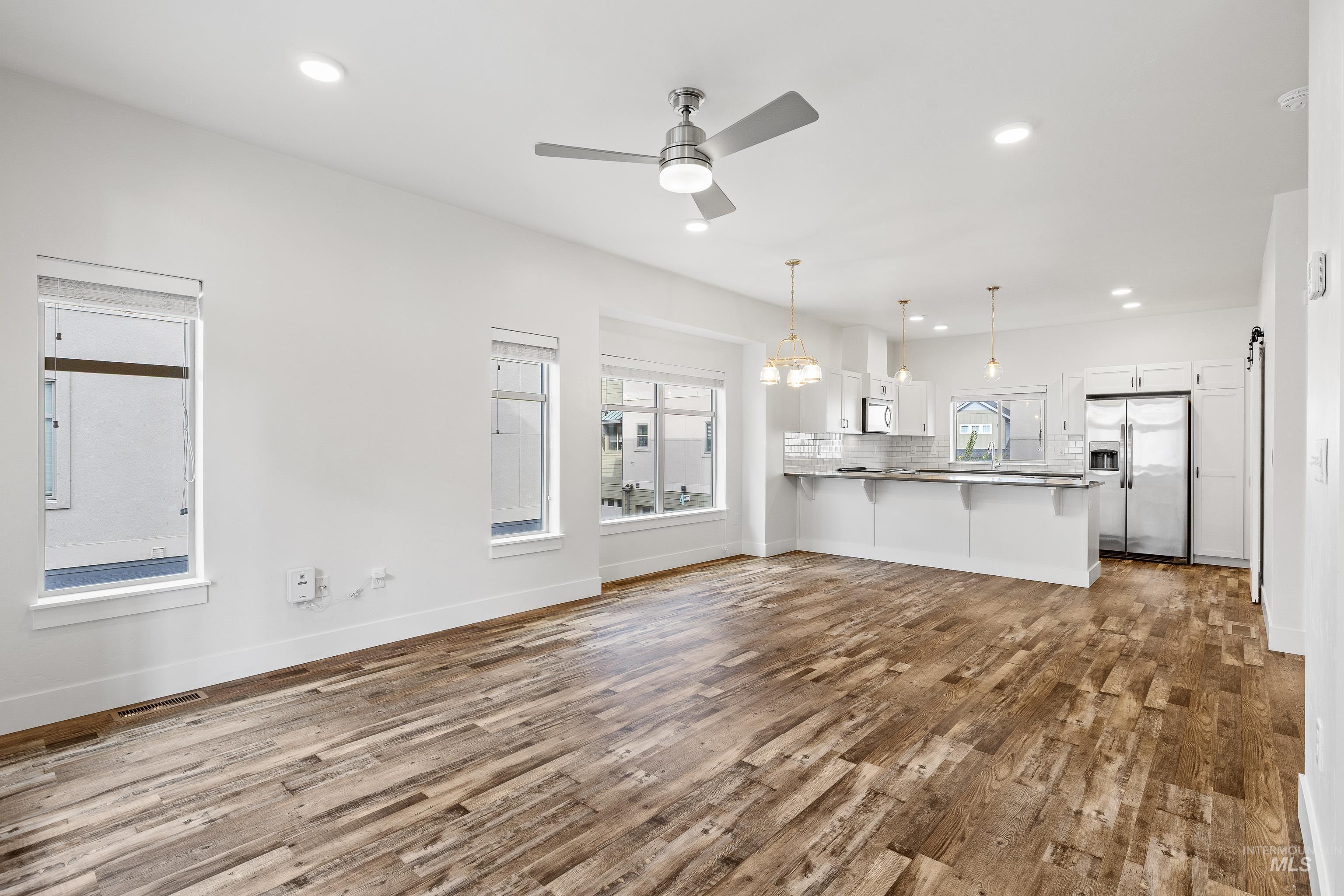 Unfurnished living room with recessed lighting, dark wood-type flooring, a chandelier, and a ceiling fan