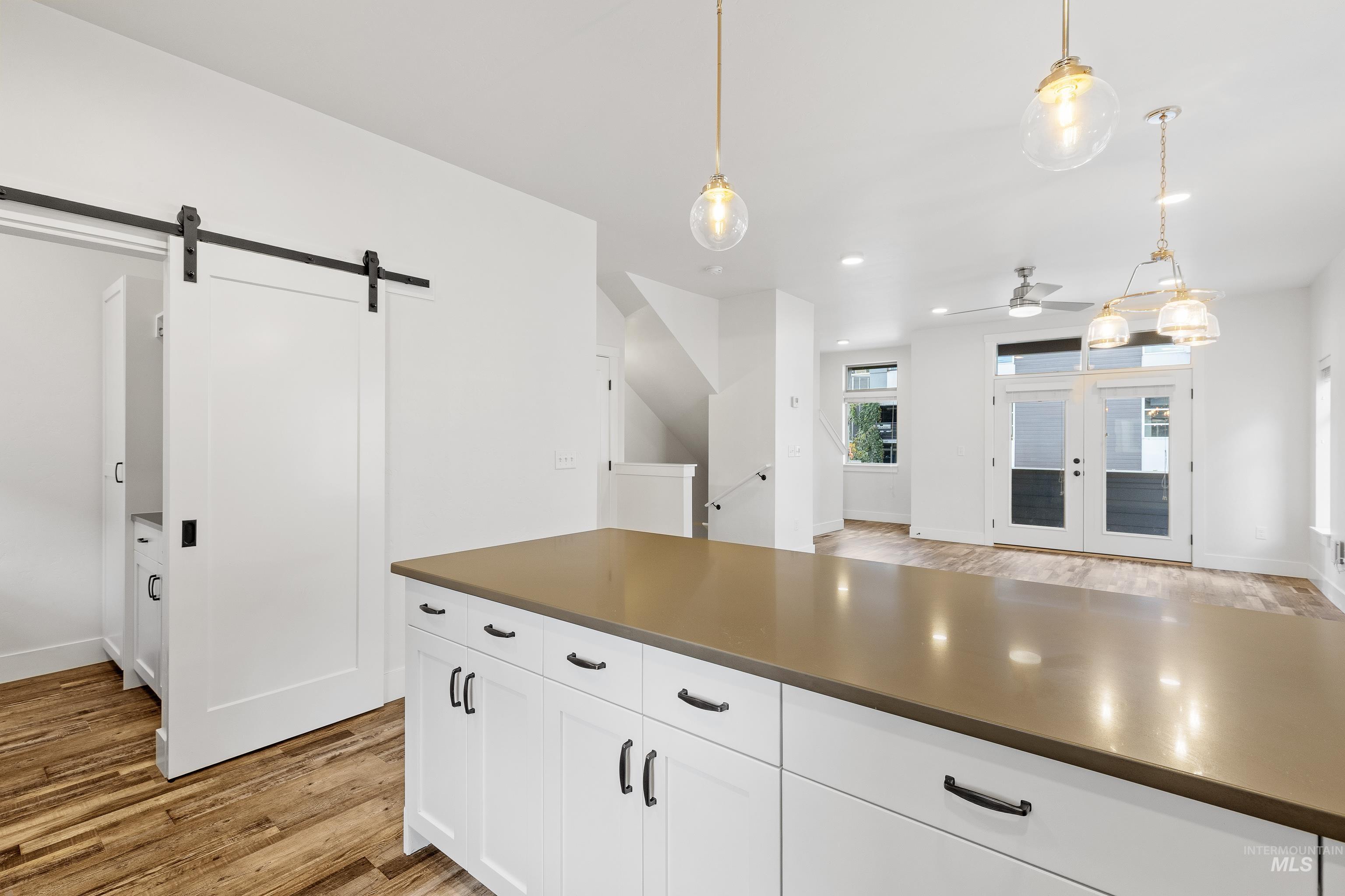 Kitchen with light wood finished floors, white cabinetry, french doors, recessed lighting, and hanging light fixtures
