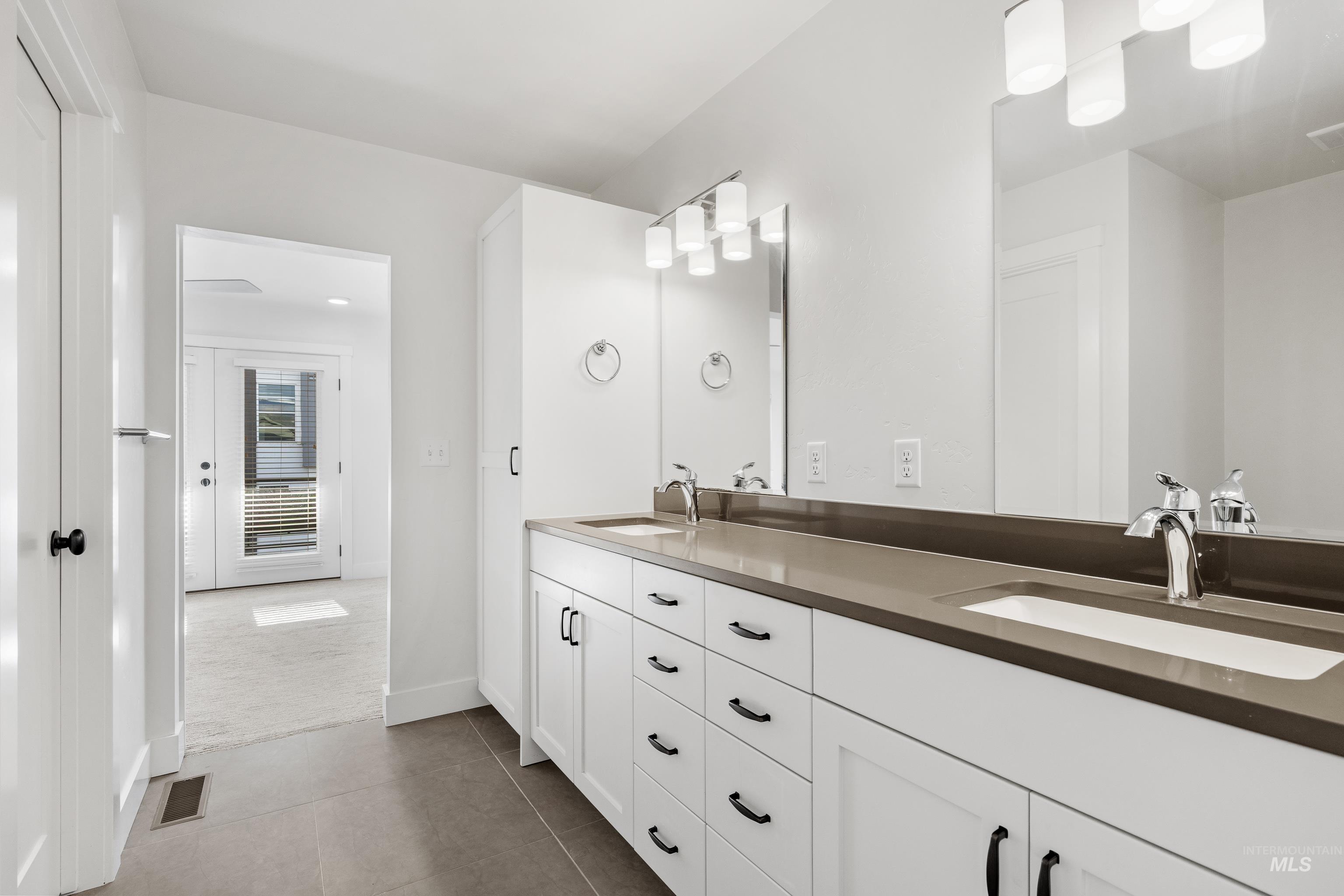 Bathroom featuring light colored carpet, double vanity, and light tile patterned floors