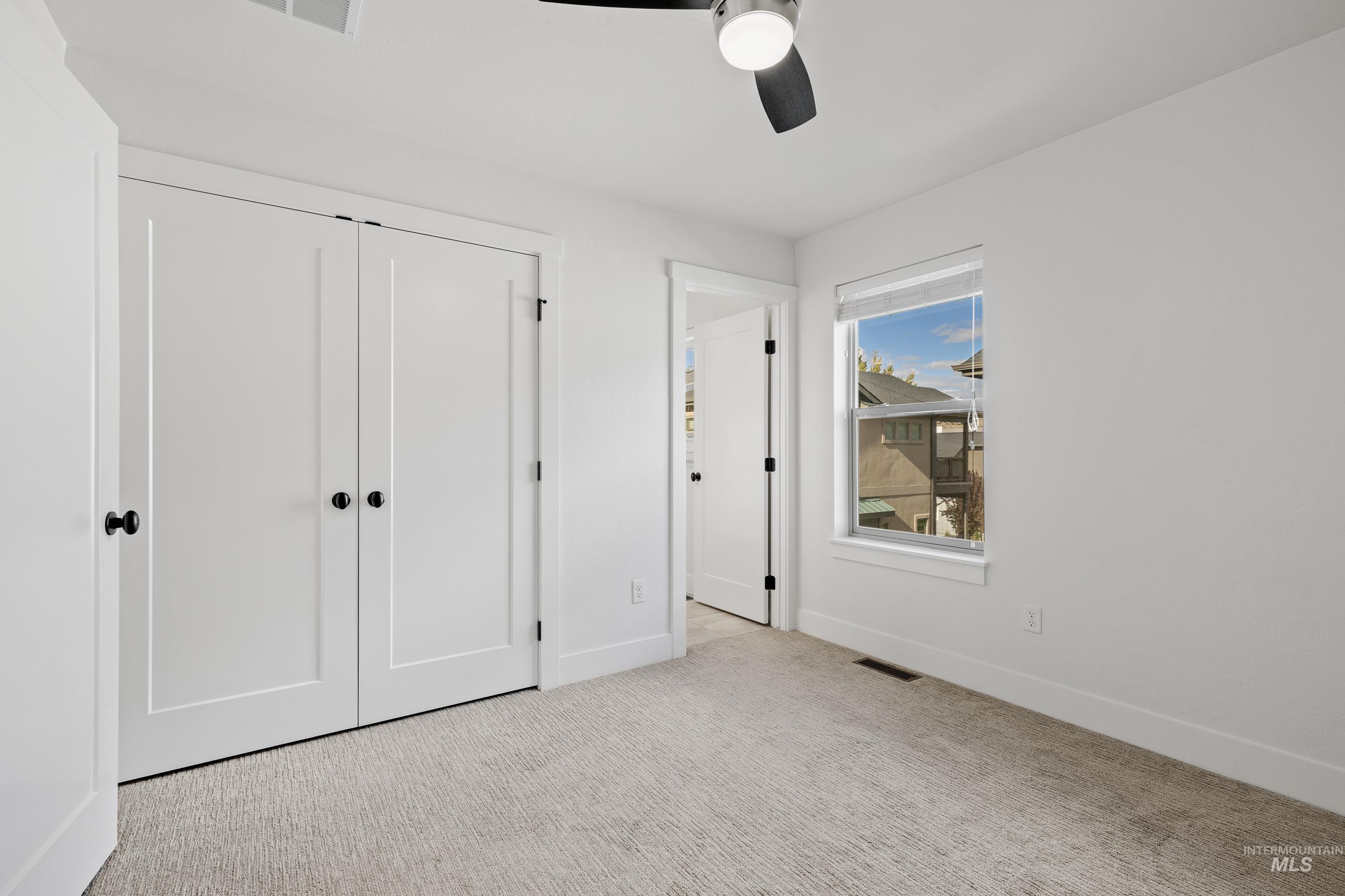Unfurnished bedroom with light carpet, a closet, and a ceiling fan