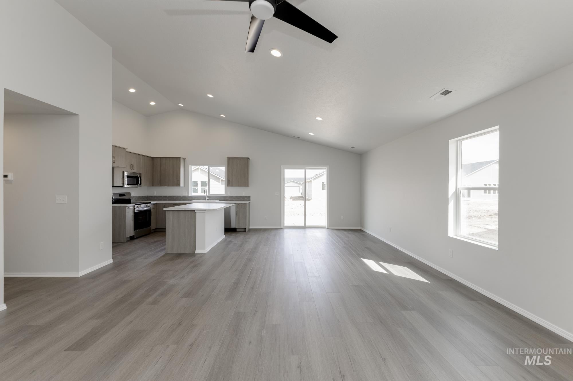 Kitchen with open floor plan, plenty of natural light, stainless steel appliances, high vaulted ceiling, and recessed lighting